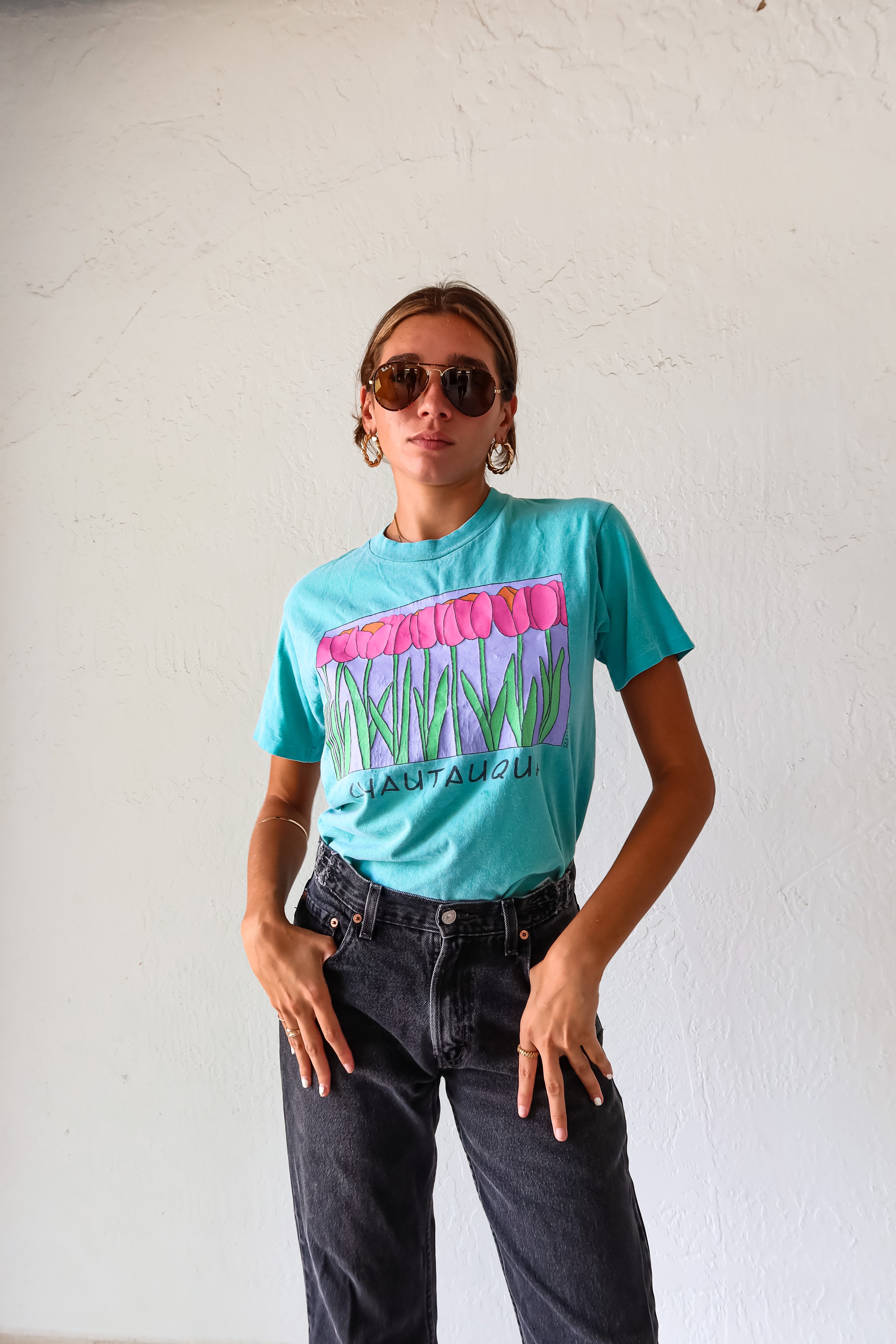 Unleash your inner vintage lover with the CHAUTAUQUA DECO VINTAGE TEE. This aqua tee features a playful botanic design and fits sizes S-L. Made from 100% cotton in the USA for a comfortable fit.