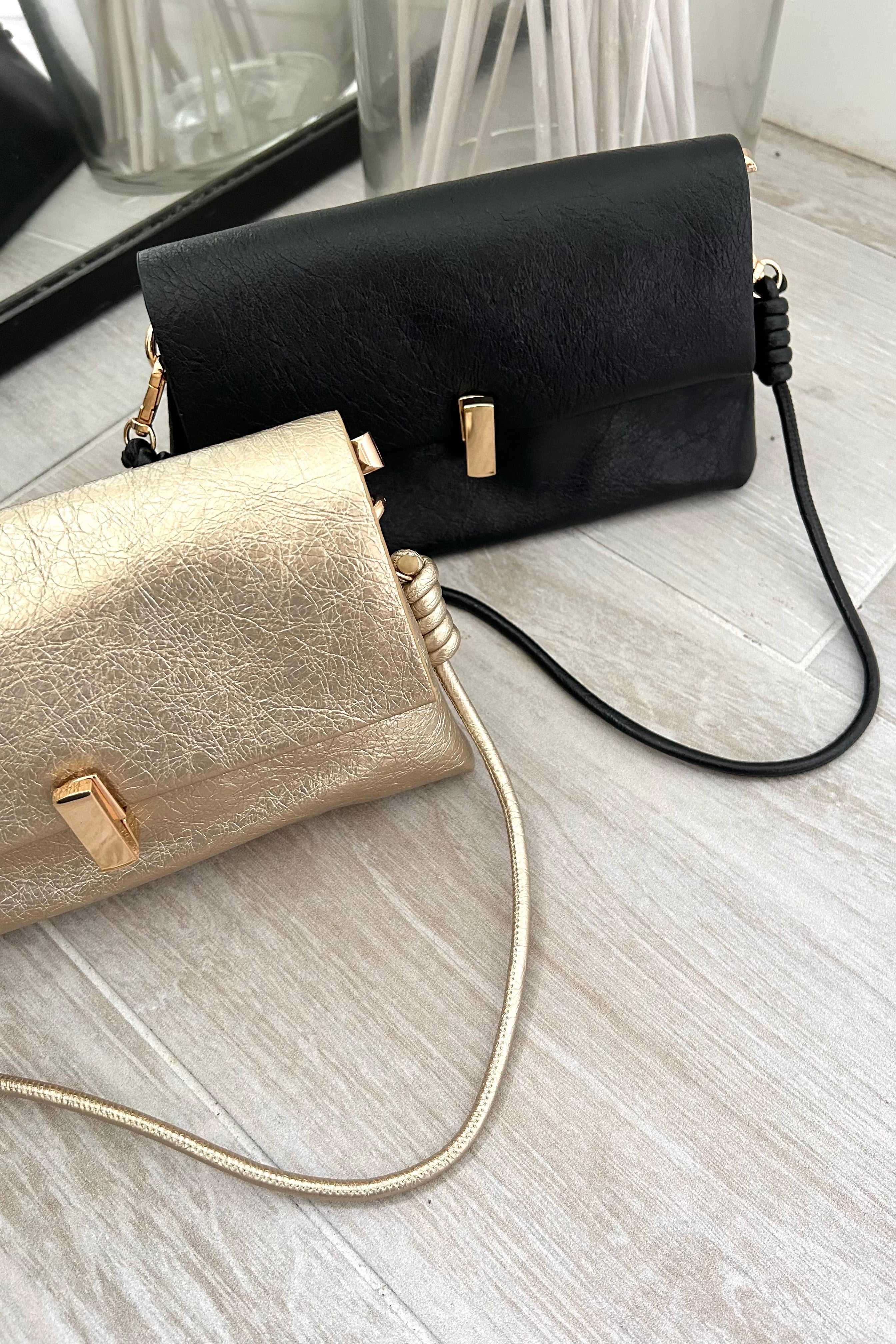 Introducing the LEXI PURSE - the perfect accessory for any outfit! Made with black or gold vegan leather, this purse is both stylish and sustainable. Carry it with ease thanks to the removable hand strap and secure your belongings with the gold buckle closure.