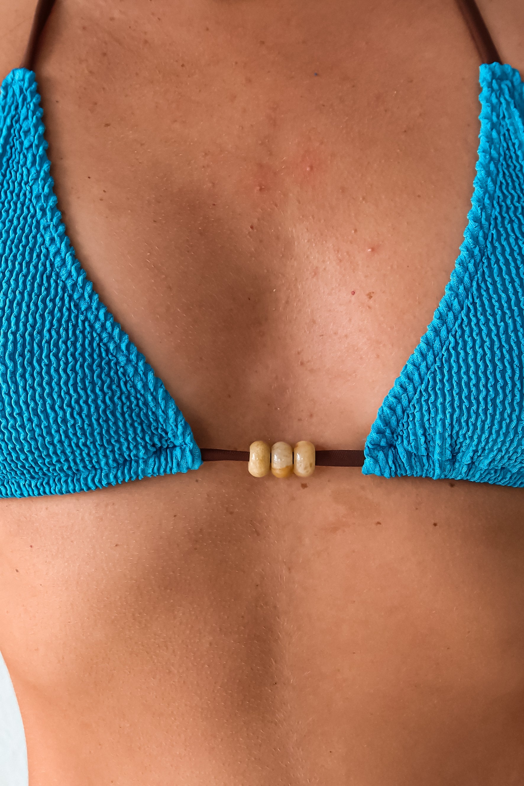Make a splash in our OCEANSIDE ONE SIZE BIKINI SET! This smocked blue bikini with a brown tie string offers a minimalist sliding triangle top and a high leg Brazilian cut bottom, perfect for XS-L. With semi precious stone beads. Hand wash cold for easy care. Dive in with ALILA swim!