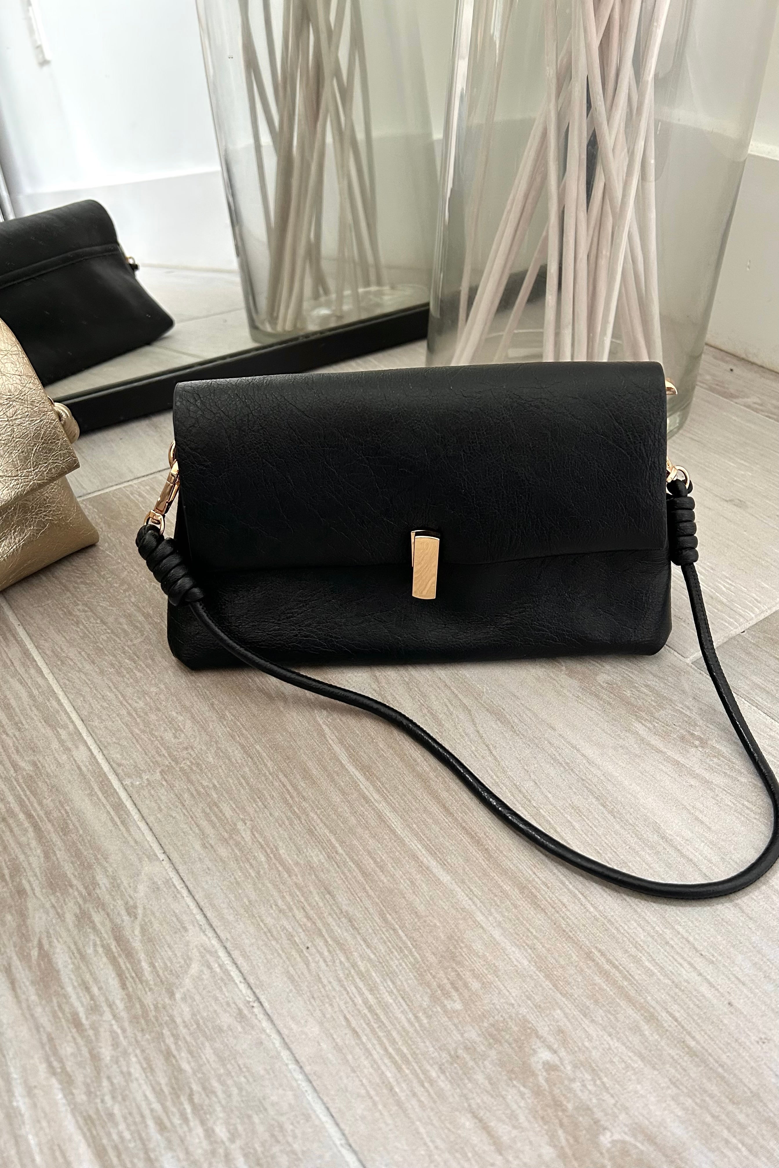 Introducing the LEXI PURSE - the perfect accessory for any outfit! Made with black or gold vegan leather, this purse is both stylish and sustainable. Carry it with ease thanks to the removable hand strap and secure your belongings with the gold buckle closure.