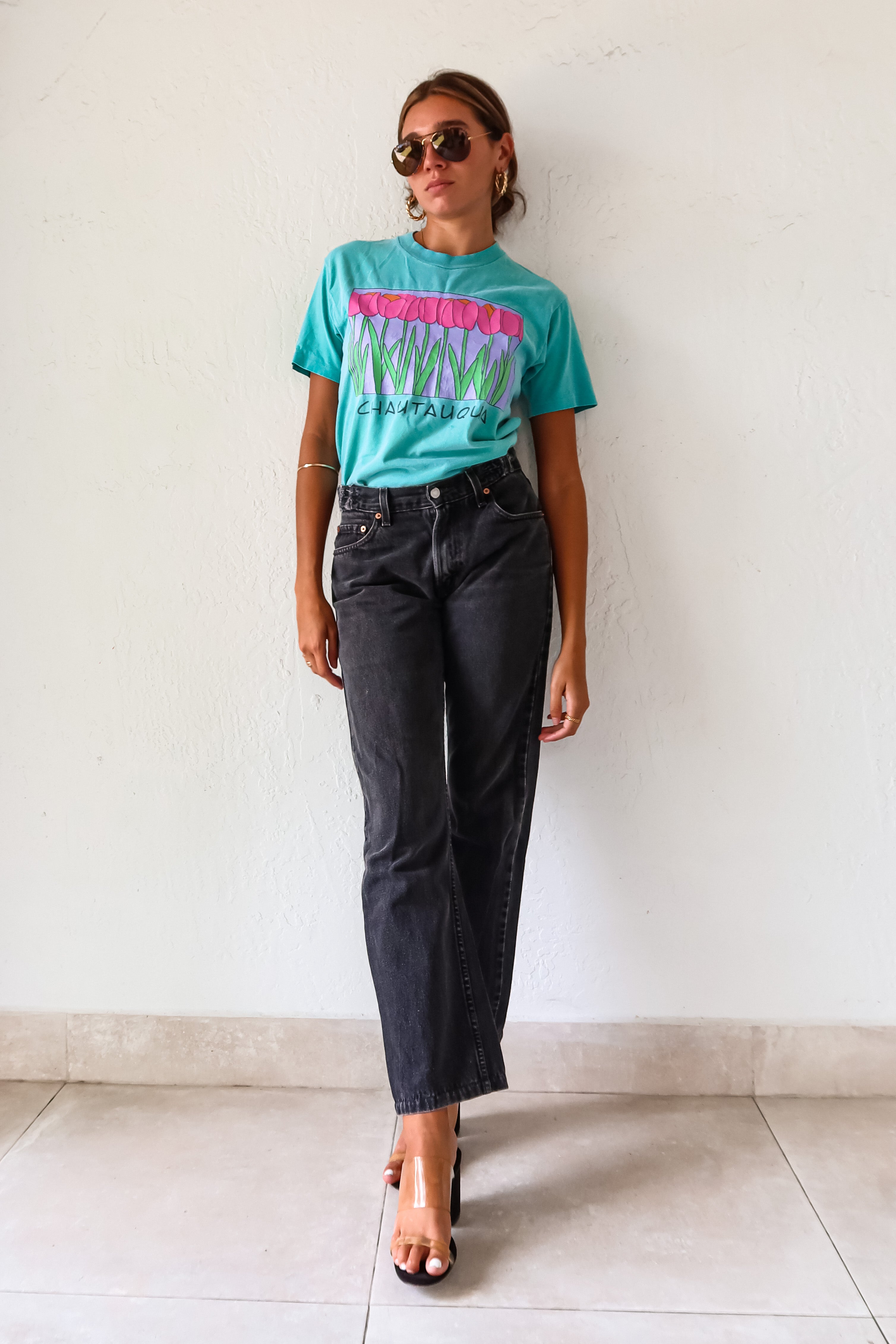 Unleash your inner vintage lover with the CHAUTAUQUA DECO VINTAGE TEE. This aqua tee features a playful botanic design and fits sizes S-L. Made from 100% cotton in the USA for a comfortable fit.