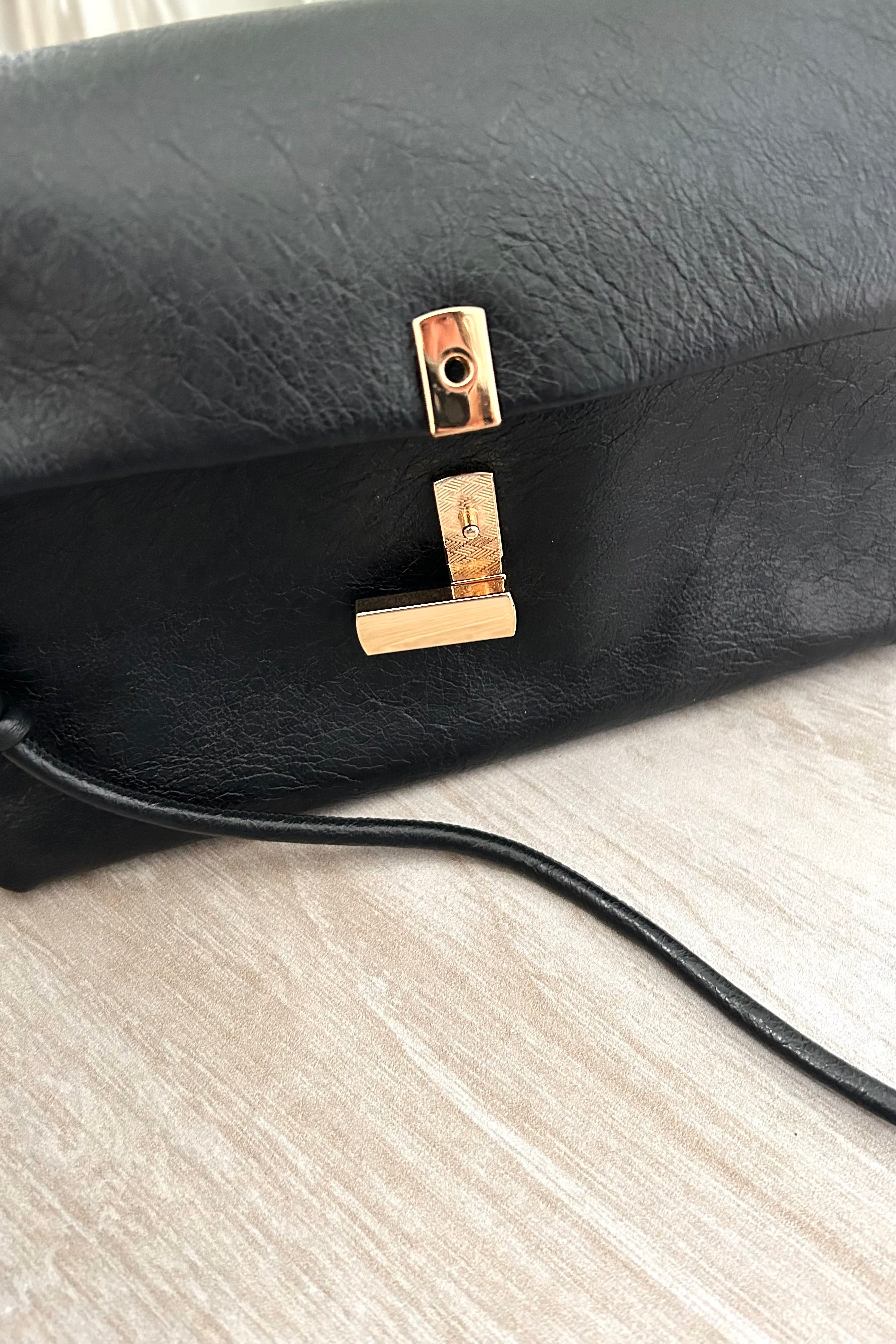 Introducing the LEXI PURSE - the perfect accessory for any outfit! Made with black or gold vegan leather, this purse is both stylish and sustainable. Carry it with ease thanks to the removable hand strap and secure your belongings with the gold buckle closure.