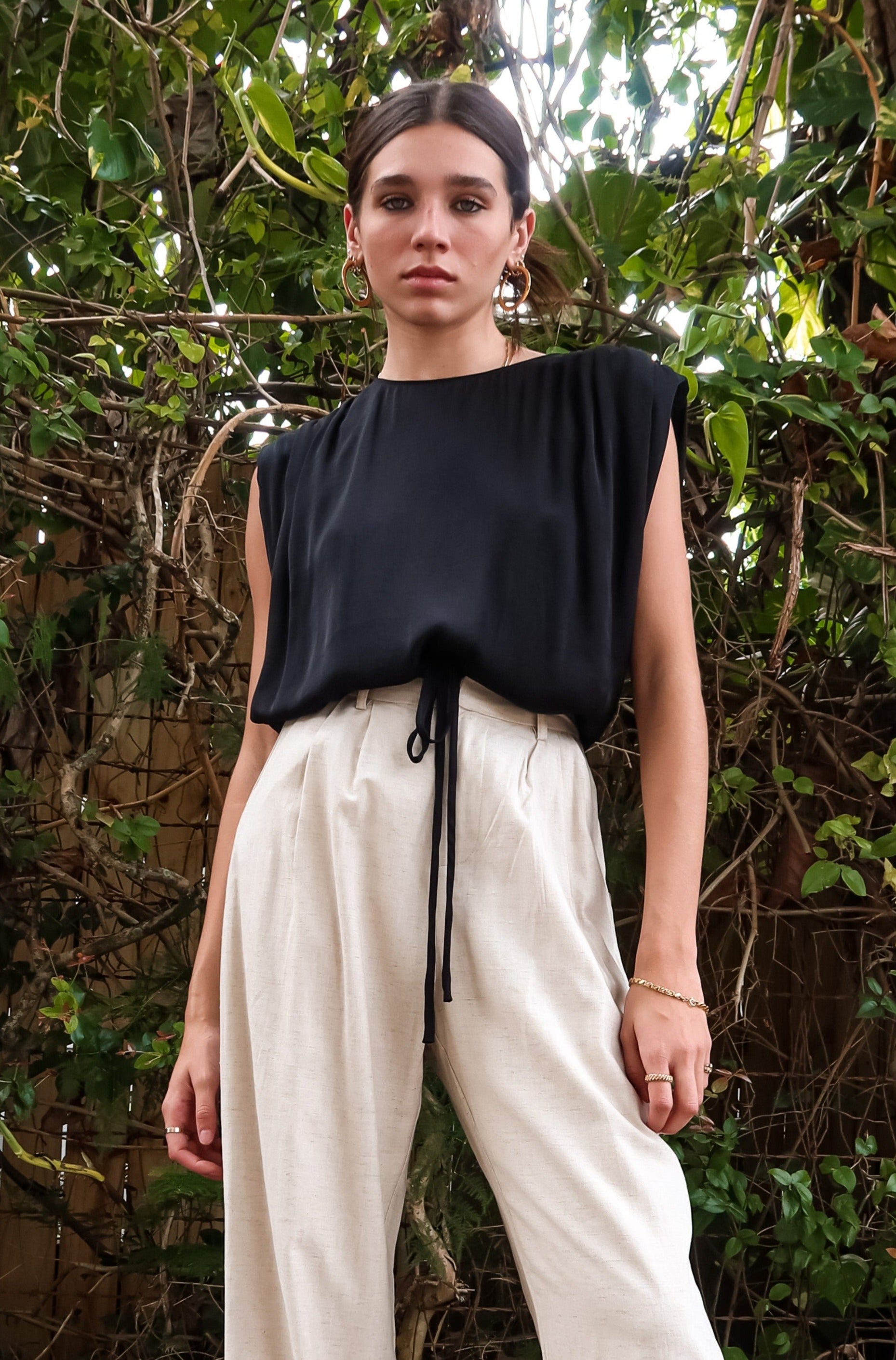 BRICKELL SATIN TOP - BLACK. This black satin top features padded shoulders and an adjustable bottom hem drawstring for ultimate comfort. Complete with a back button closure and made with polyester material,
