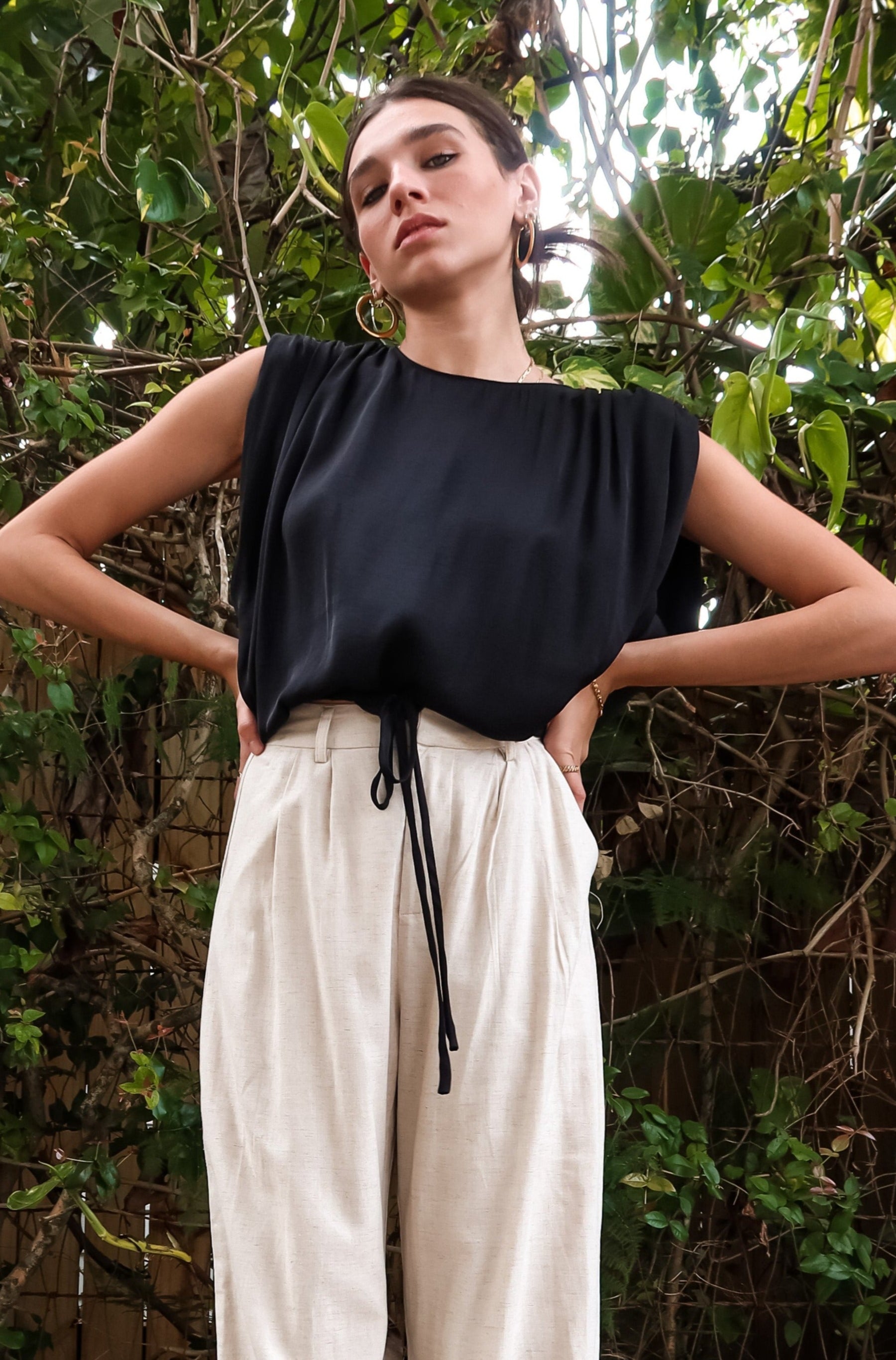 BRICKELL SATIN TOP - BLACK. This black satin top features padded shoulders and an adjustable bottom hem drawstring for ultimate comfort. Complete with a back button closure and made with polyester material,