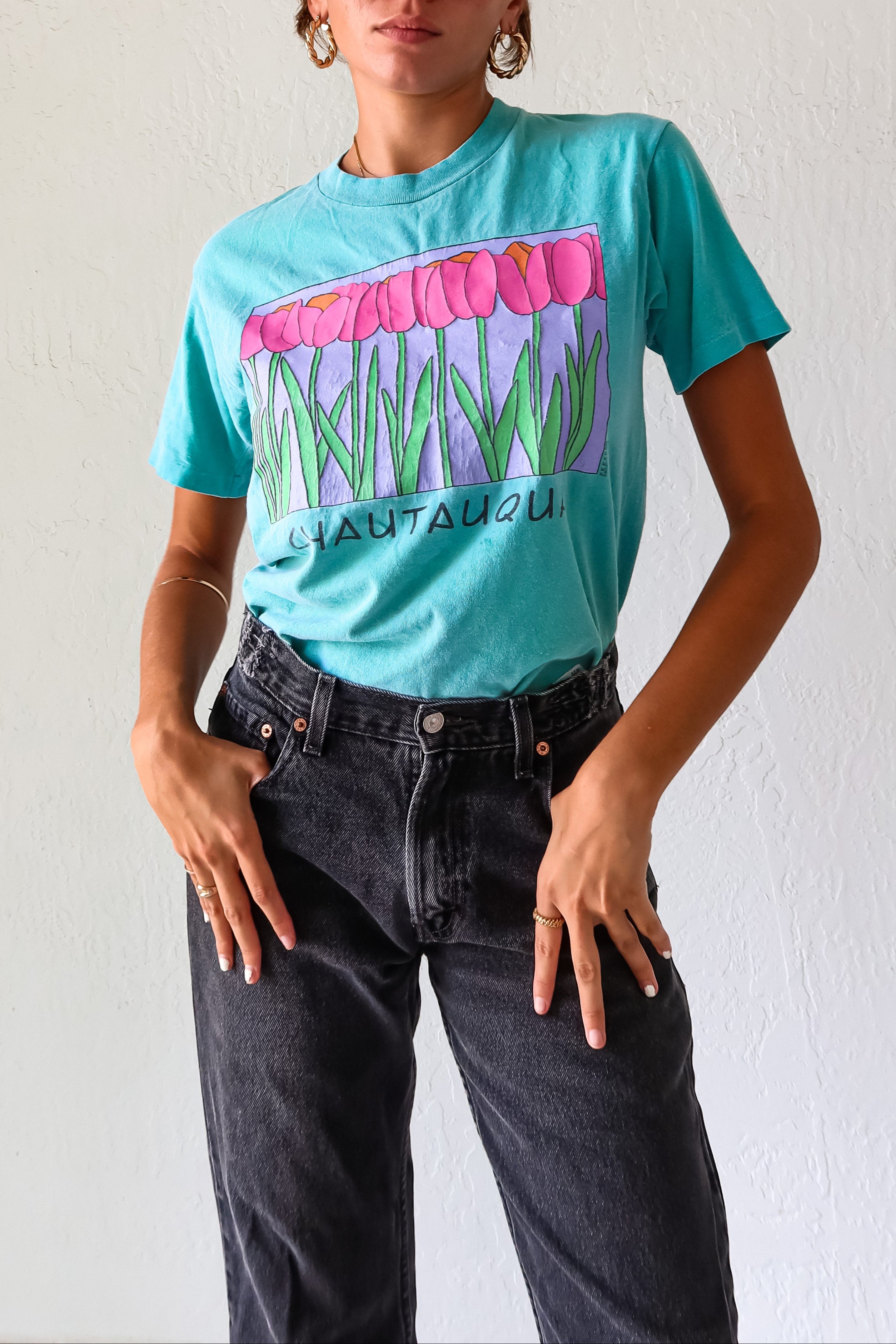 Unleash your inner vintage lover with the CHAUTAUQUA DECO VINTAGE TEE. This aqua tee features a playful botanic design and fits sizes S-L. Made from 100% cotton in the USA for a comfortable fit. 