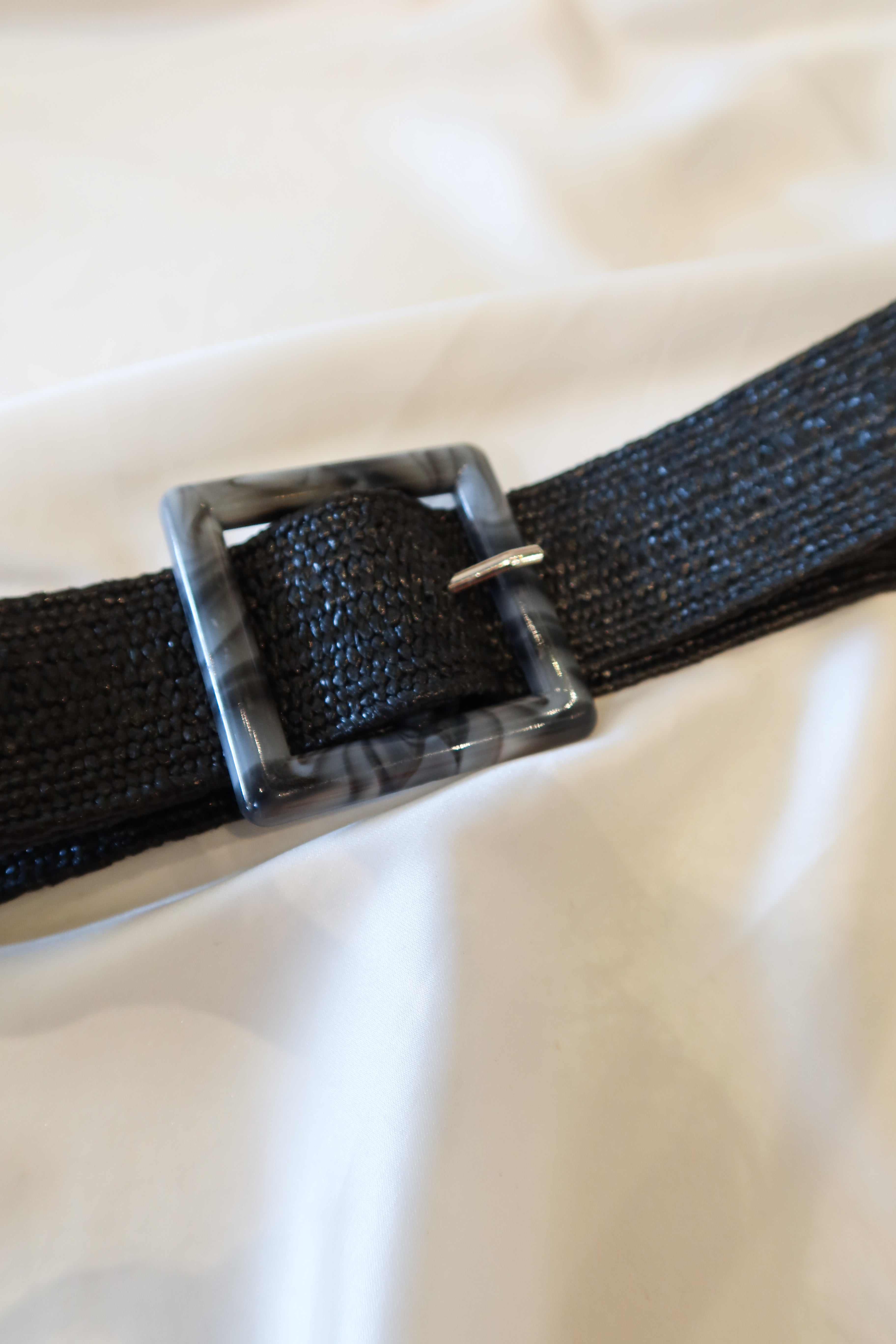 Unleash your style with our Marbled Stretch Belt! This black woven belt features a unique grey and black marble buckle and stretchy fabric for a comfortable fit. One size fits all for endless possibilities. Upgrade your wardrobe today!