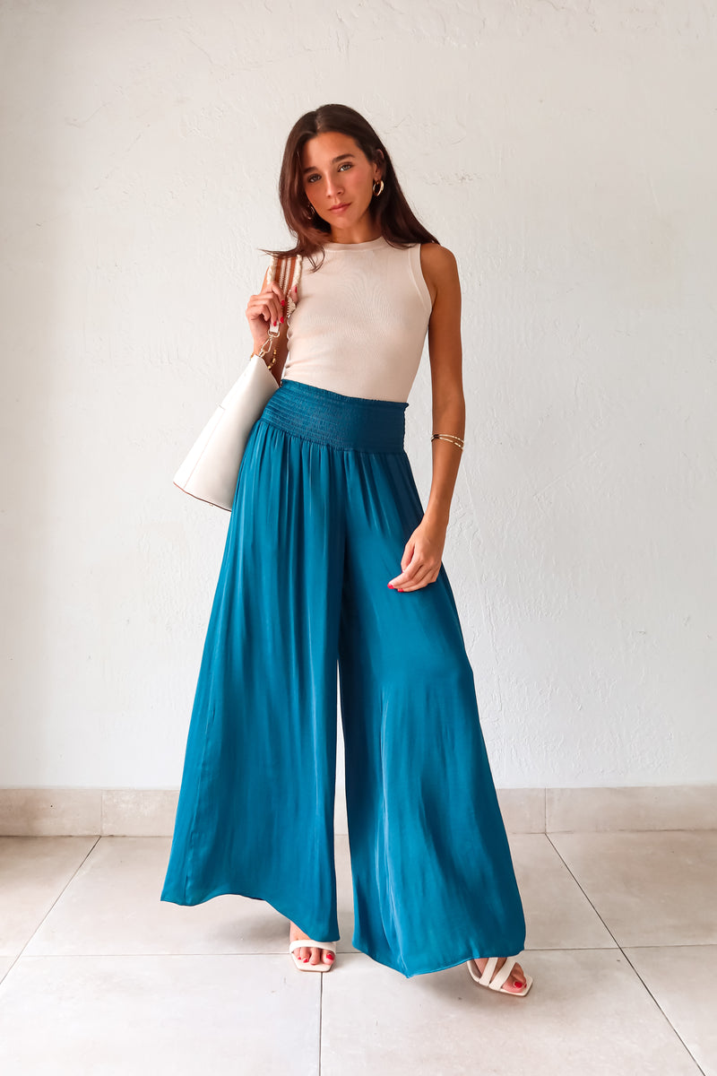 Get ready to make a statement in our MONDRIAN SATIN PANT. The lagoon blue satin fabric exudes luxury and the smocked waist ensures a comfortable fit. With a wide leg design, these pants will elevate any outfit, making you look and feel confident.