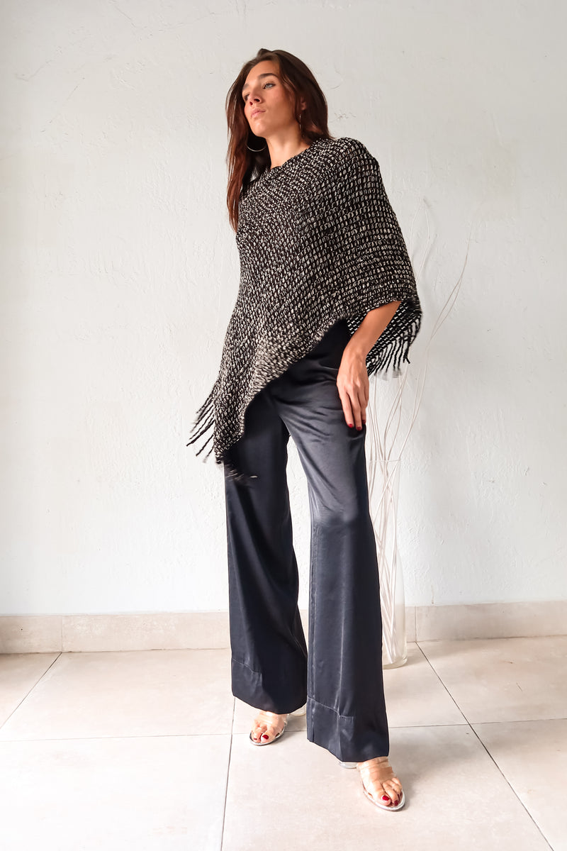 Embrace your wild side with our FULL MOON LUREX PONCHO. The black lurex sweater poncho features silver fabric detailing, a fringed bottom, and stretchy fabric for a comfortable fit that flatters any size. Perfect for a night out or cozying up by the fire. One size fits XS-L.