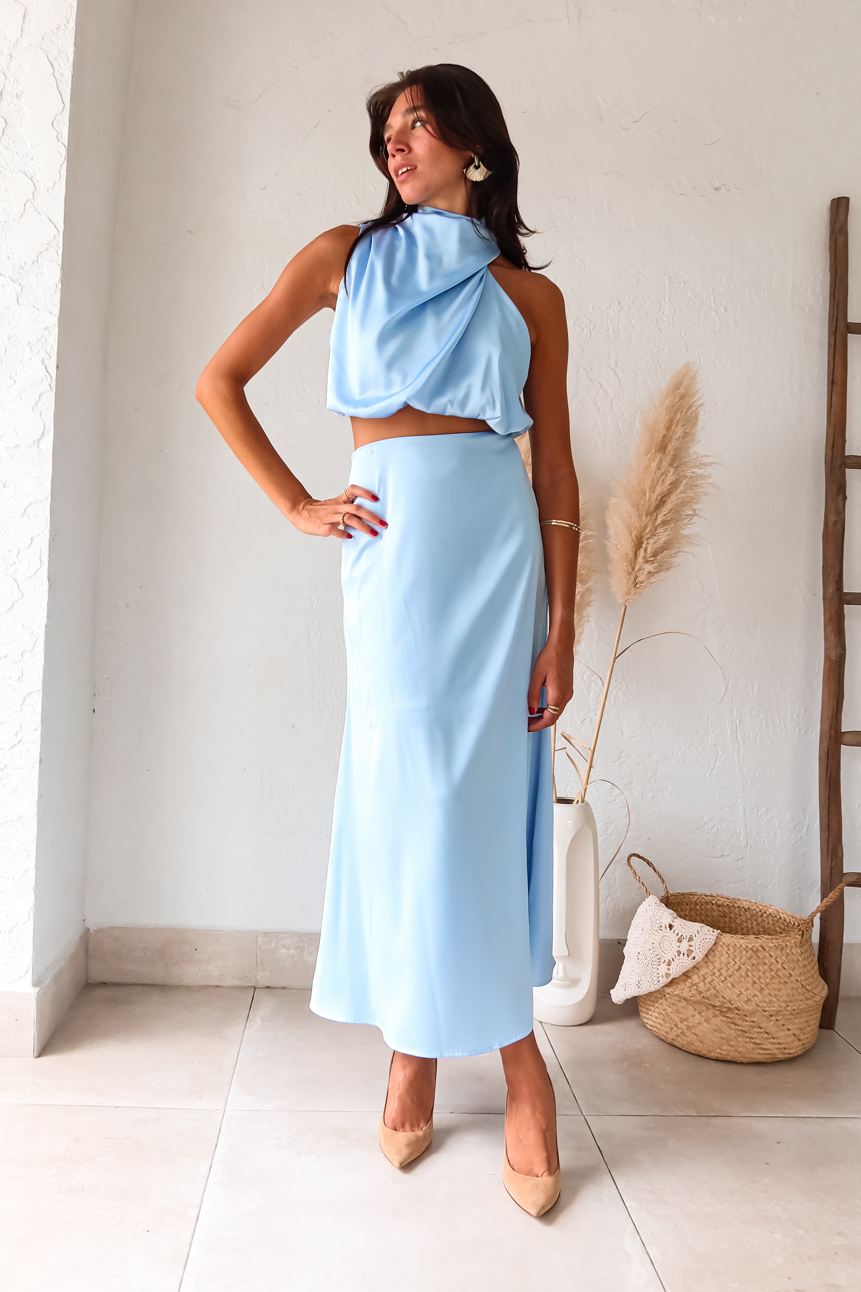 Look effortlessly chic in our Bellagio Satin Skirt Set! This sky blue stunner features a high neck asymmetrical top with functional buttons for added detail. The elastic scrunch fit ensures all day comfort, while the matching maxi skirt with side zipper closure adds a touch of elegance.