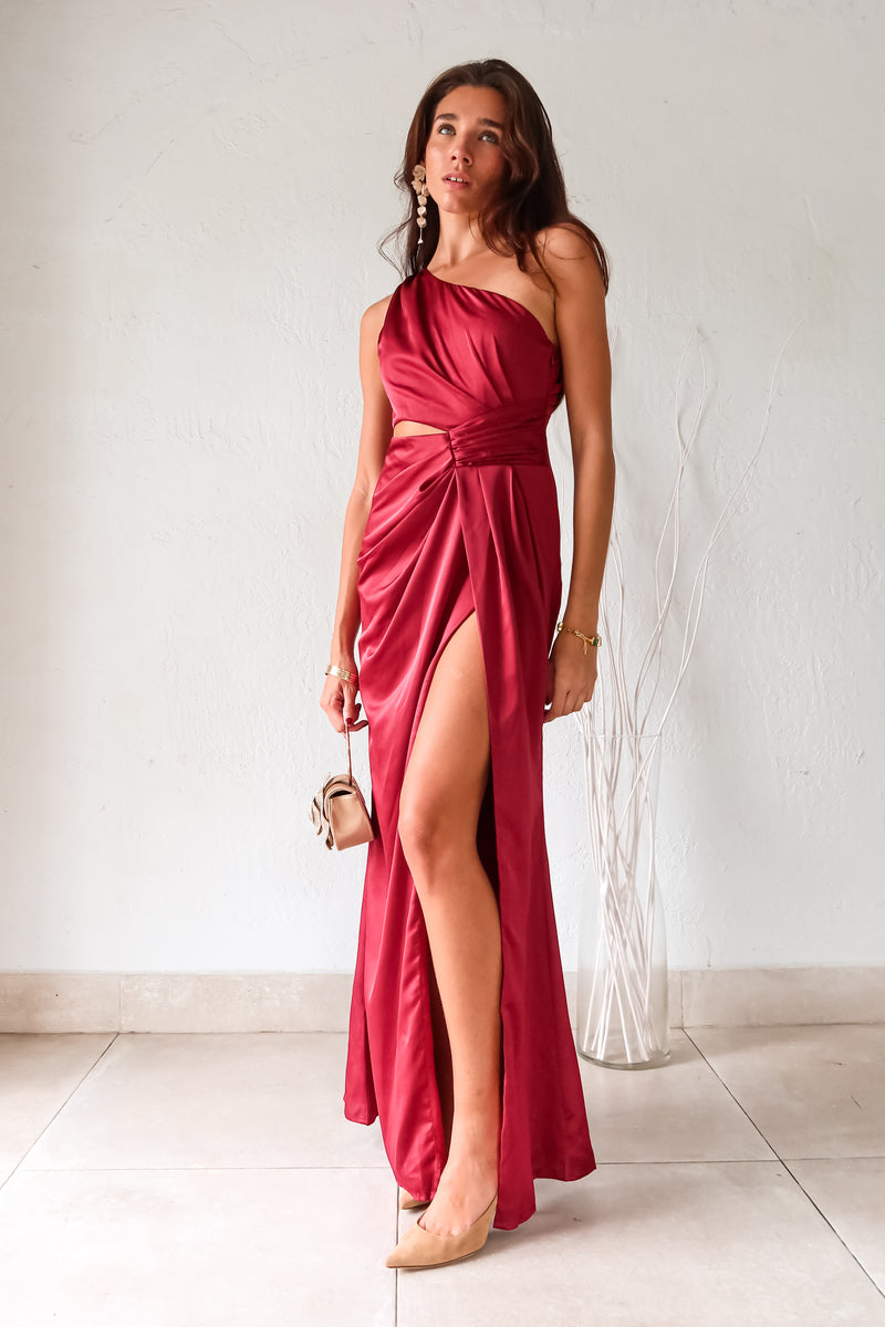 Indulge in the wine red NAPA VALLEY SATIN MAXI DRESS - a playful twist on a classic silhouette. The asymmetrical design features a right torso slit and left leg slit, while the side zipper closure adds a touch of convenience. Effortlessly chic and undeniably unique, this dress is perfect for any occasion.