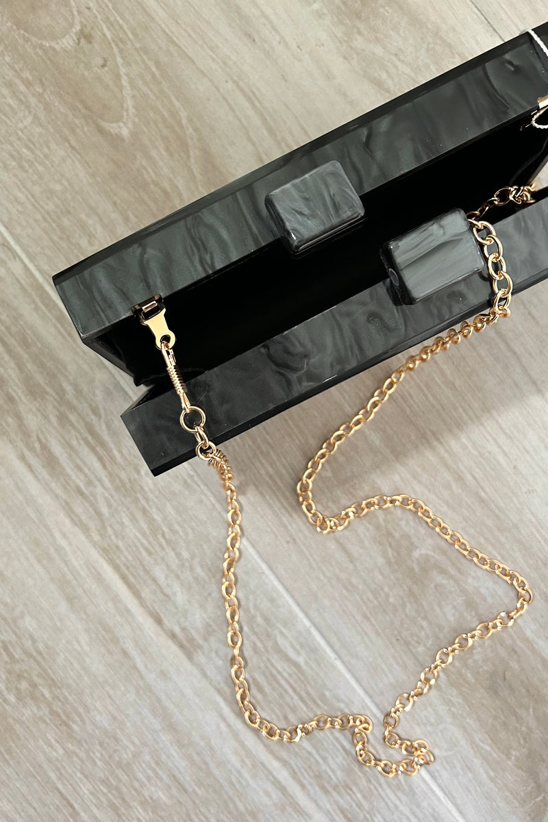 Keep your style on point with our EVIL EYE ACRYLIC CLUTCH. Made from sleek black marble acrylic, this clutch features a mesmerizing evil eye design. The removable shoulder chain adds versatility and allows you to rock the clutch in different ways.