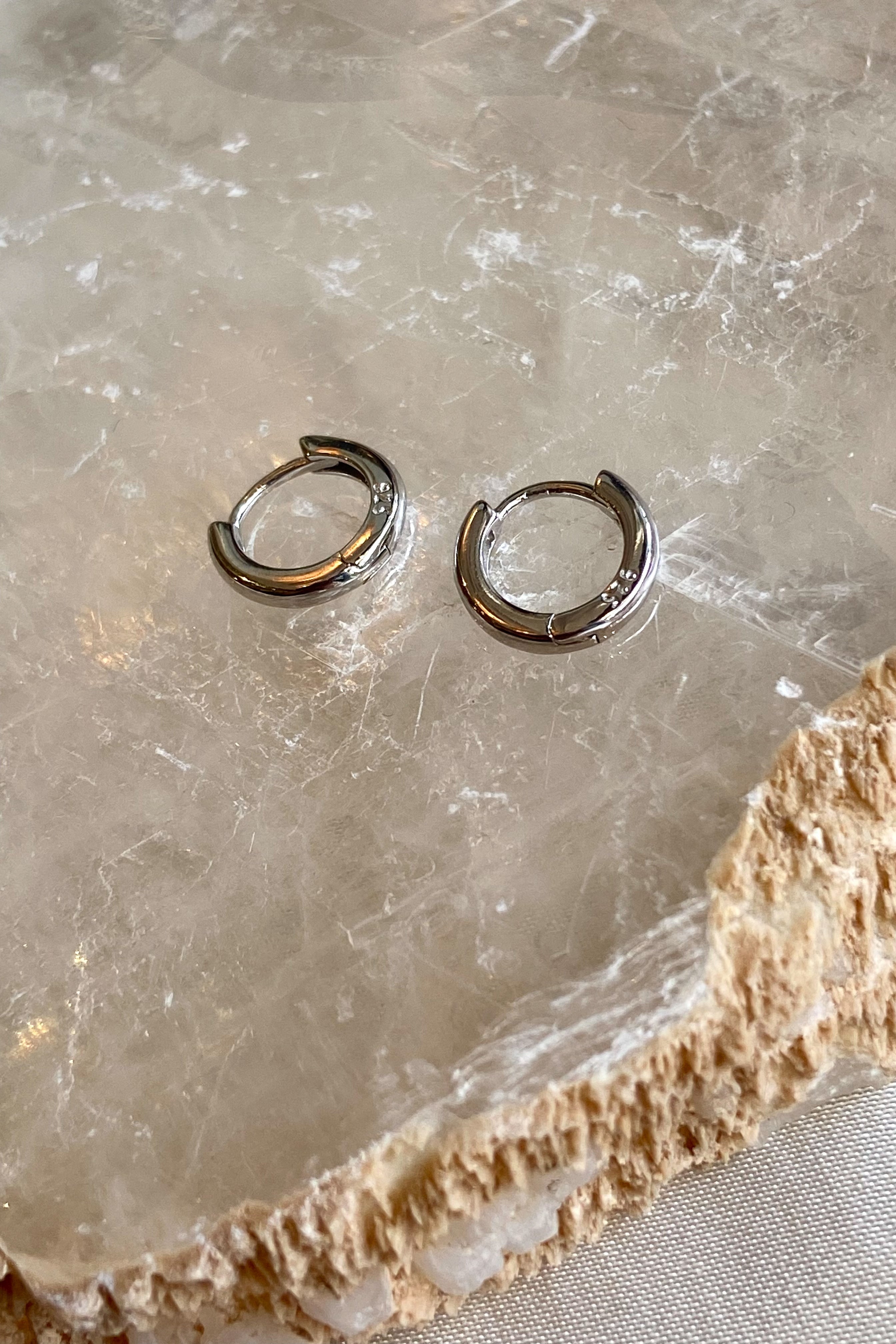 Take your everyday hoop earrings to the next level with our SILVER PLATED HOOP HUGGIES! Crafted from 925 sterling silver, these huggies are hypoallergenic and tarnish resistant, making them perfect for sensitive ears. Elevate your style with these unique and versatile earrings!