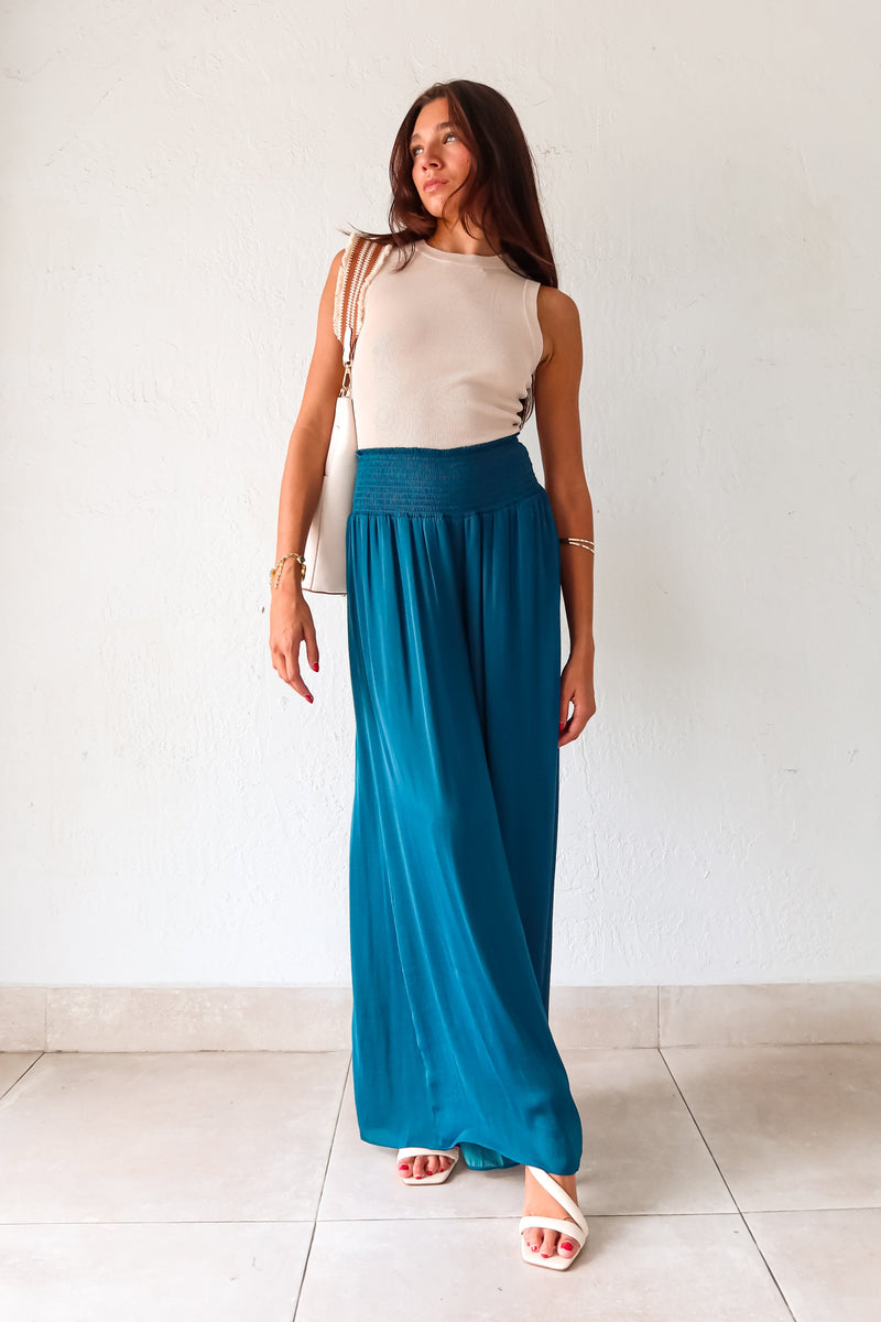 Get ready to make a statement in our MONDRIAN SATIN PANT. The lagoon blue satin fabric exudes luxury and the smocked waist ensures a comfortable fit. With a wide leg design, these pants will elevate any outfit, making you look and feel confident.