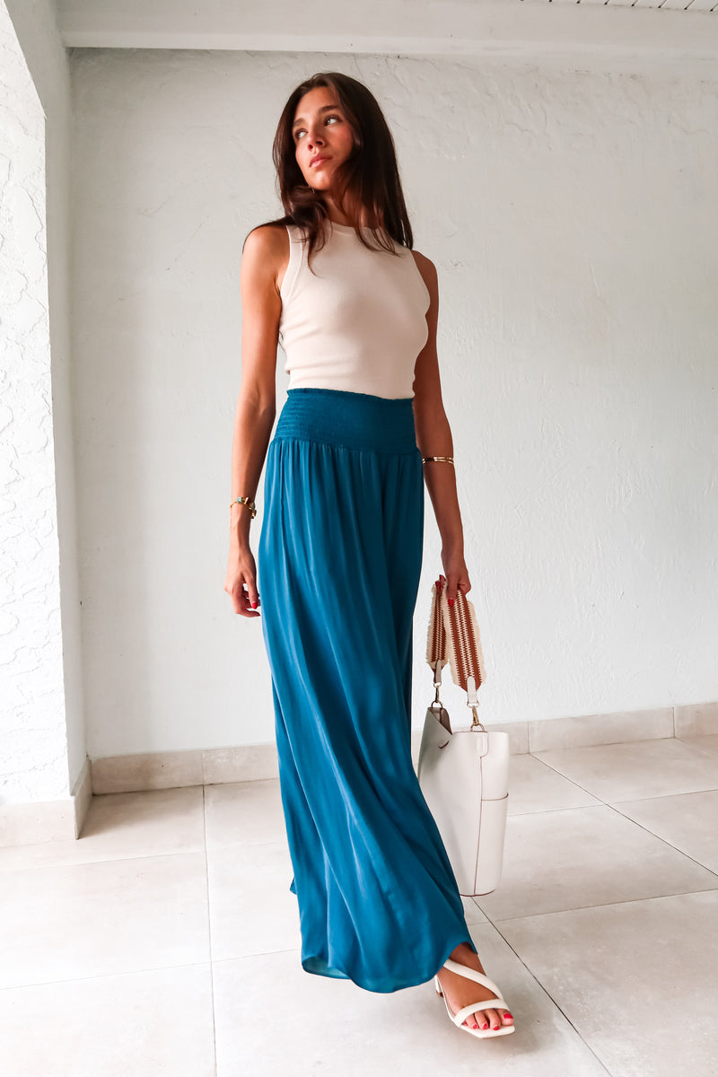 Get ready to make a statement in our MONDRIAN SATIN PANT. The lagoon blue satin fabric exudes luxury and the smocked waist ensures a comfortable fit. With a wide leg design, these pants will elevate any outfit, making you look and feel confident.