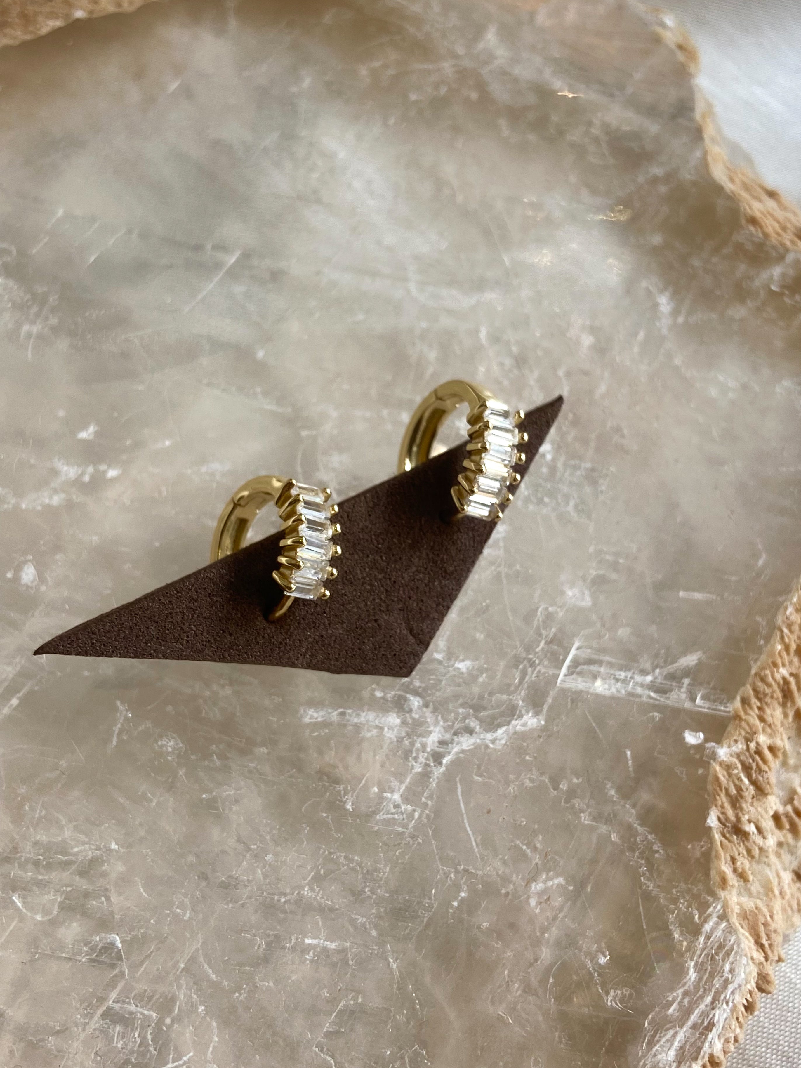 Get ready to fall in love with these Baguette Huggie Earrings! Made with 925 sterling silver and gold plating, these earrings are both stylish and hypoallergenic. Made with tarnish-resistant materials, they'll keep you looking and feeling your best. Upgrade your earring game today!