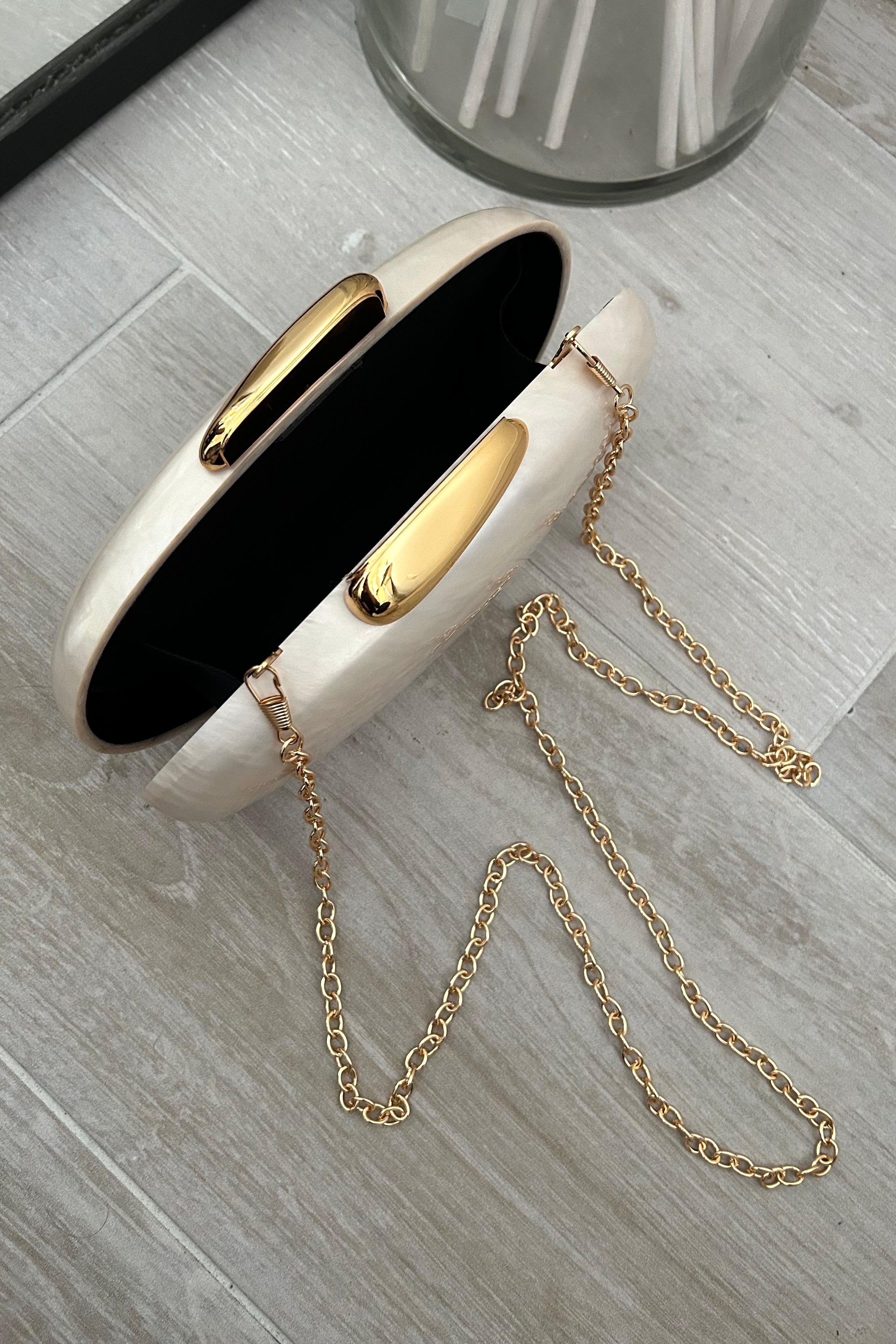 Get ready to slay any event with the FREYA CLUTCH! Made from stunning pearl acrylic, this clutch features a gold clip closure for a touch of elegance. And with a removable shoulder strap, you can go from classy clutch to chic crossbody in seconds.