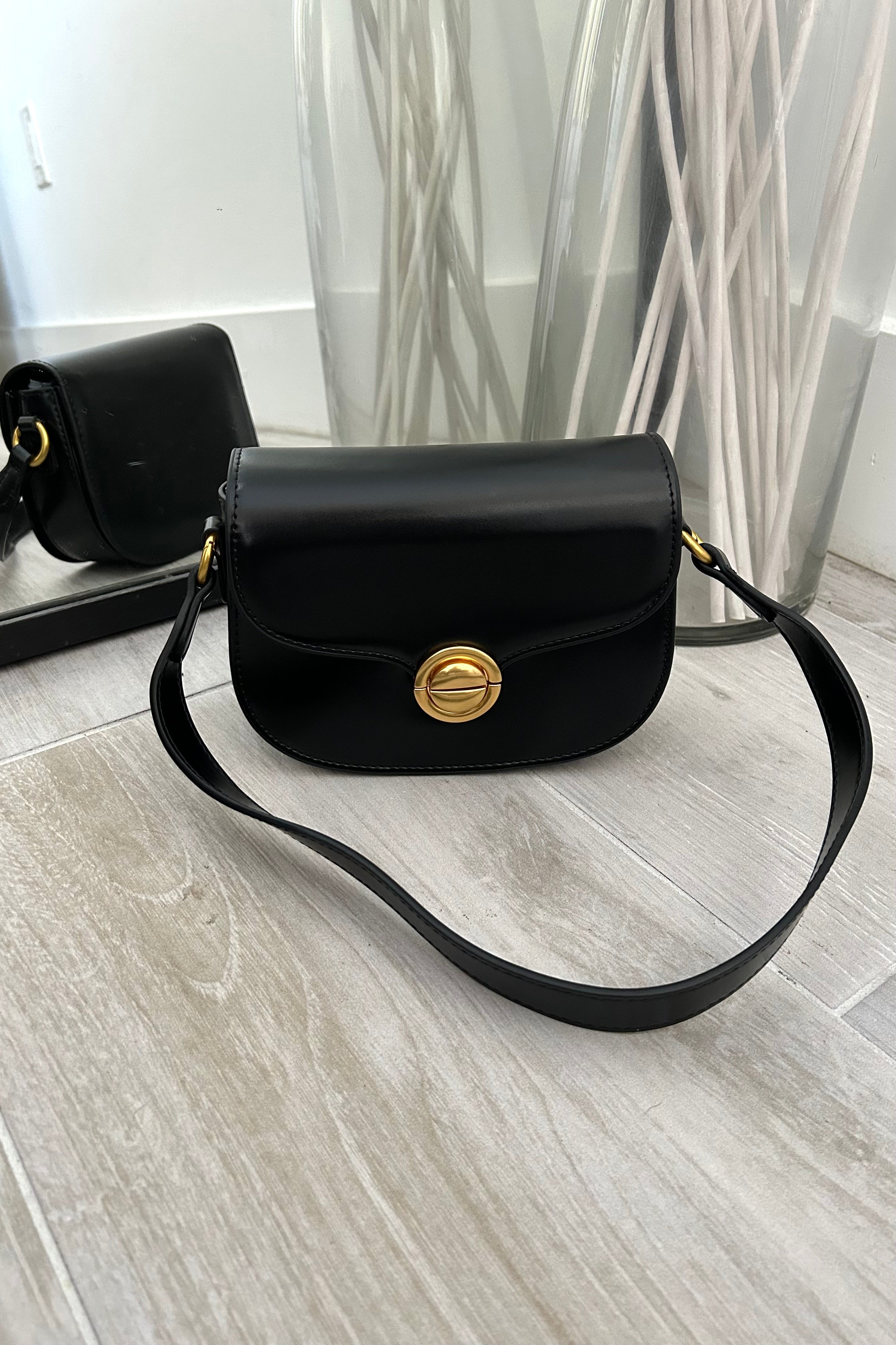 Take the spotlight with our HOLLYWOOD PURSE. This sleek black vegan leather purse features a glamorous gold clip front closure and removable shoulder straps for versatile styling. Elevate your accessory game and turn heads with this must-have purse. 