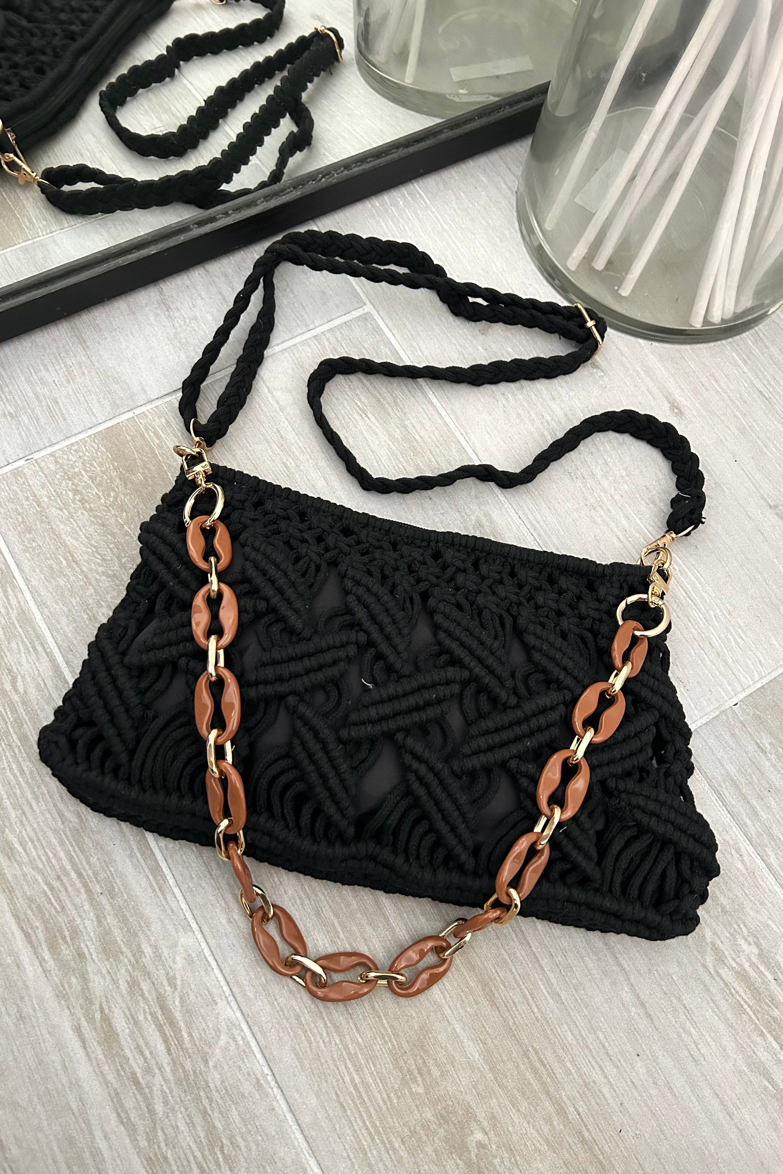 This black knit handbag adds a touch of boho-chic to any outfit. The acrylic gold hand strap and removable straps offer versatility, while the zipper closure keeps your belongings secure. Measuring 11 inches in length, 7 inches in height, and 1 inch in width, it's the perfect size for all your essentials.