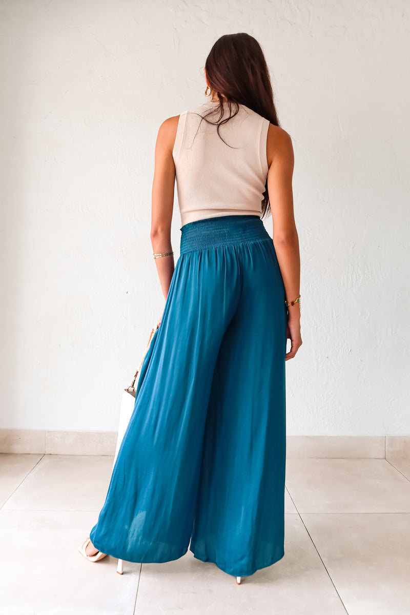 Get ready to make a statement in our MONDRIAN SATIN PANT. The lagoon blue satin fabric exudes luxury and the smocked waist ensures a comfortable fit. With a wide leg design, these pants will elevate any outfit, making you look and feel confident.