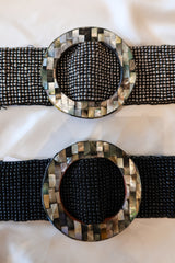 OZ Beaded Belt! Handcrafted in Bali, this stretchy and versatile belt features a unique abalone circle buckle and beautiful black or silver beading. One size fits all, making it the perfect accessory for any outfit.