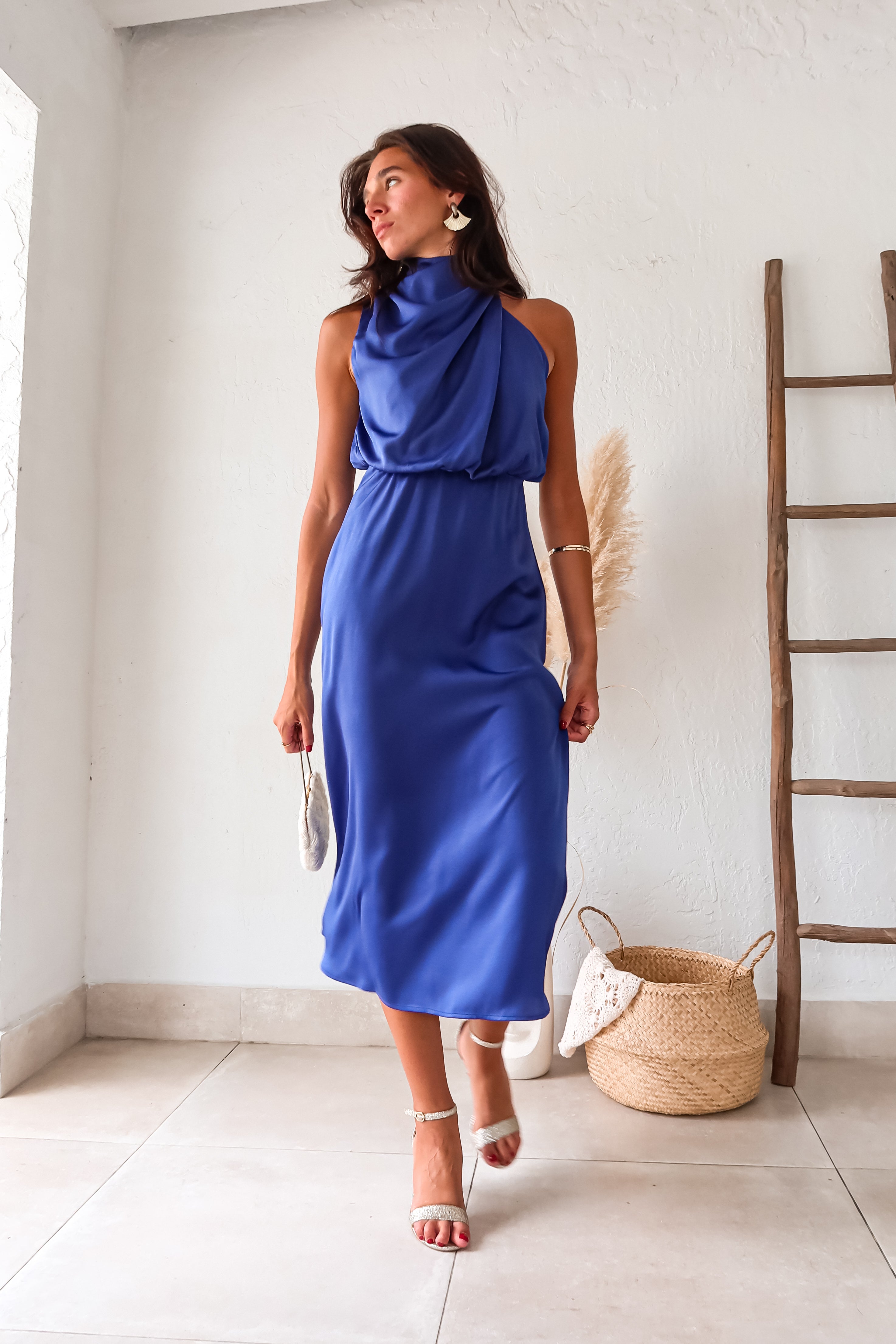 Indulge in luxurious comfort with the Bellagio Satin Maxi Dress in navy. The high neck and asymmetrical sleeveless top are accented with elegant buttons. The elastic scrunch torso and waist backing provide a comfortable fit, while the top is lined for added coverage.