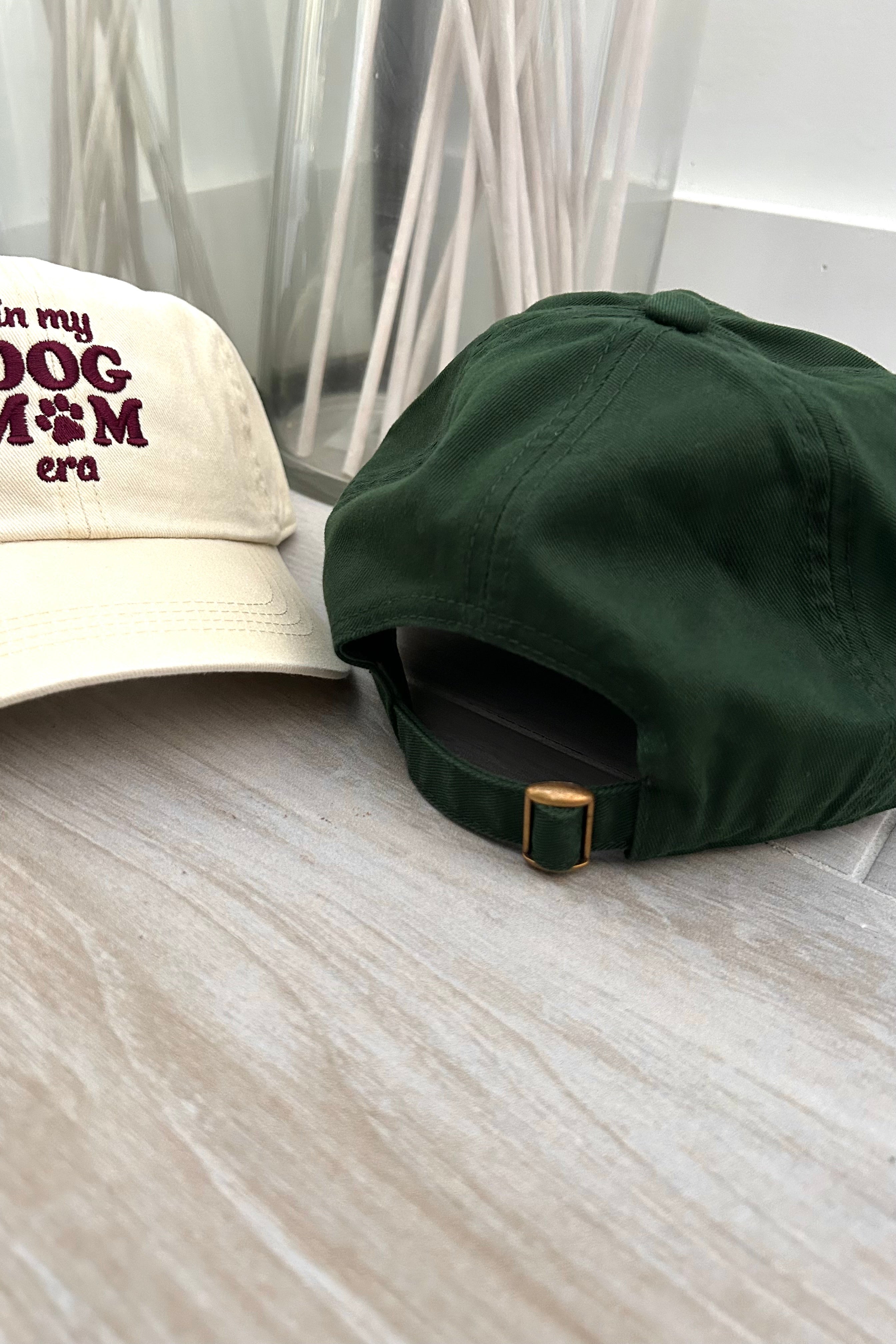 Get ready to represent all the dog moms out there with our Dog Mom Era Baseball Cap! Available in two color combinations - dark green with white letters or beige with maroon letters - and featuring an adjustable strap, this cap is both stylish and comfortable. One size fits all, so you can show off your love for your furry friend in the perfect fit.