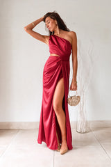 Indulge in the wine red NAPA VALLEY SATIN MAXI DRESS - a playful twist on a classic silhouette. The asymmetrical design features a right torso slit and left leg slit, while the side zipper closure adds a touch of convenience. Effortlessly chic and undeniably unique, this dress is perfect for any occasion.