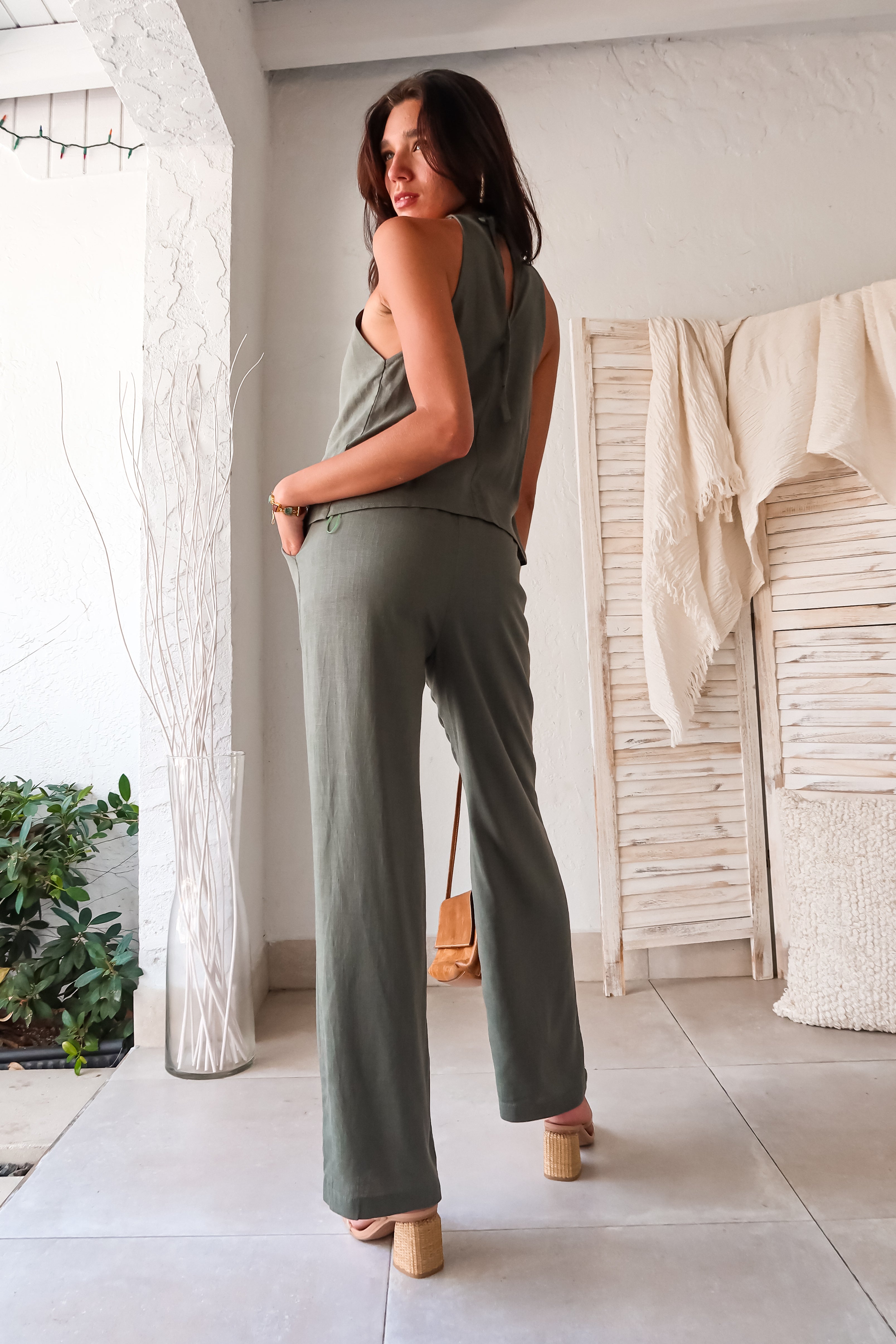 stylish in our Shoreline Linen Pant Set. This olive linen duo features a halter style top with a tie back and overlapping front for a unique touch. The elastic waistband and drawstring closure ensure a comfortable fit, while the front pockets add convenience. Perfect for warm weather,