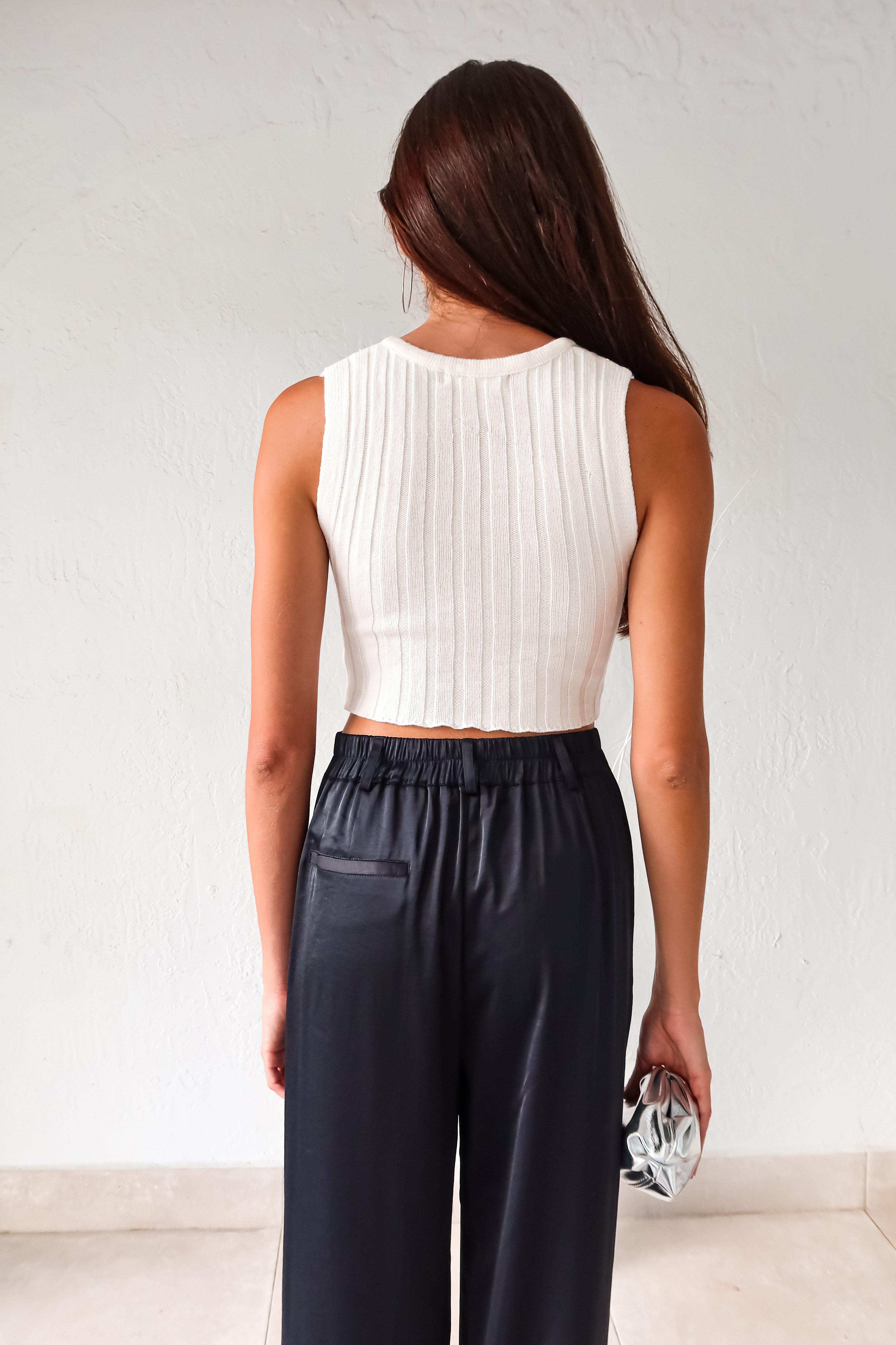 Add some edge to your wardrobe with our white ribbed crop top! Featuring a unique neck chain detail and front overlap design, this top is sure to turn heads. The stretchy fabric ensures a comfortable fit for all-day wear.