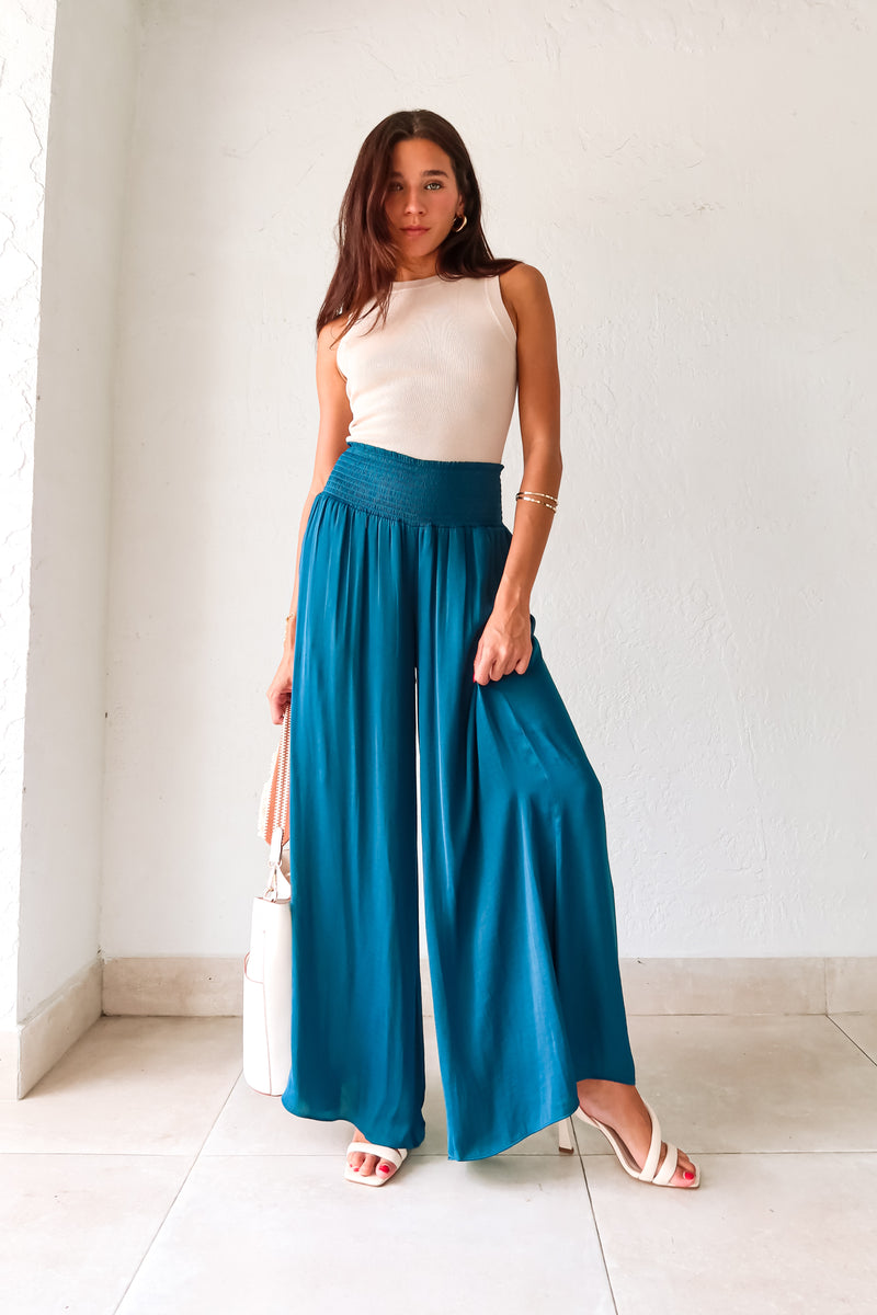 Get ready to make a statement in our MONDRIAN SATIN PANT. The lagoon blue satin fabric exudes luxury and the smocked waist ensures a comfortable fit. With a wide leg design, these pants will elevate any outfit, making you look and feel confident.