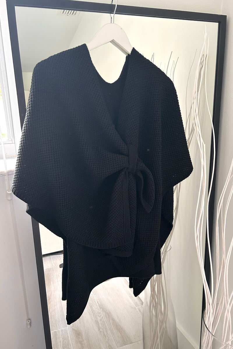 Get cozy with our Waffle Knit Poncho Cardigan! This stylish cardigan features a stretchy fabric for a comfortable fit and a unique cross body closure loop detail. Available in khaki and black, it's perfect for any occasion. Stay warm and stylish at the same time! 