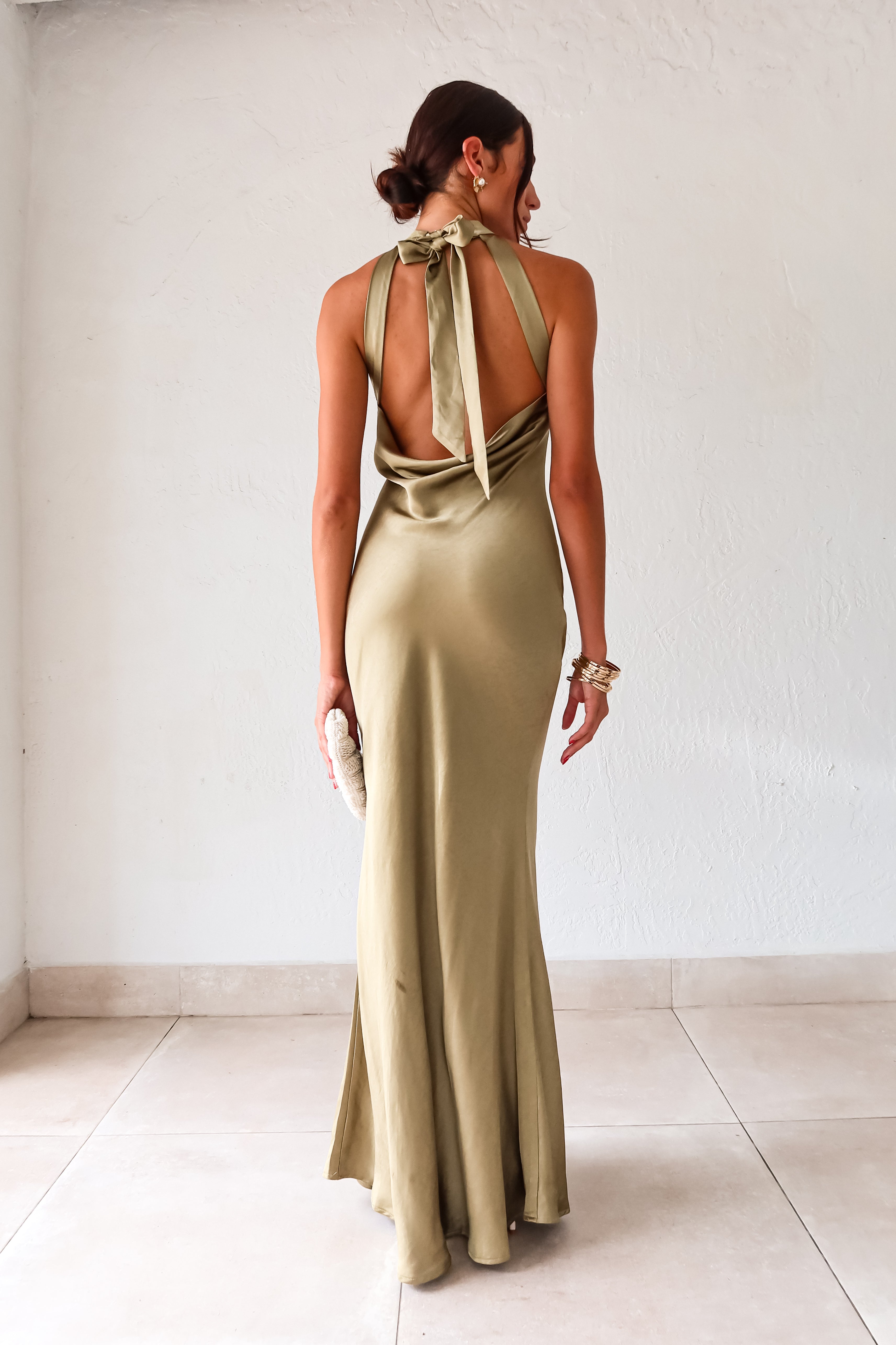 Take your style to the next level with the MAIN EVENT SATIN MAXI DRESS! This luxurious dress features a high neckline and adjustable tie in the back, perfect for creating a flattering silhouette. The draped back adds a touch of elegance to complete your look. Dress to impress with this stunning piece.