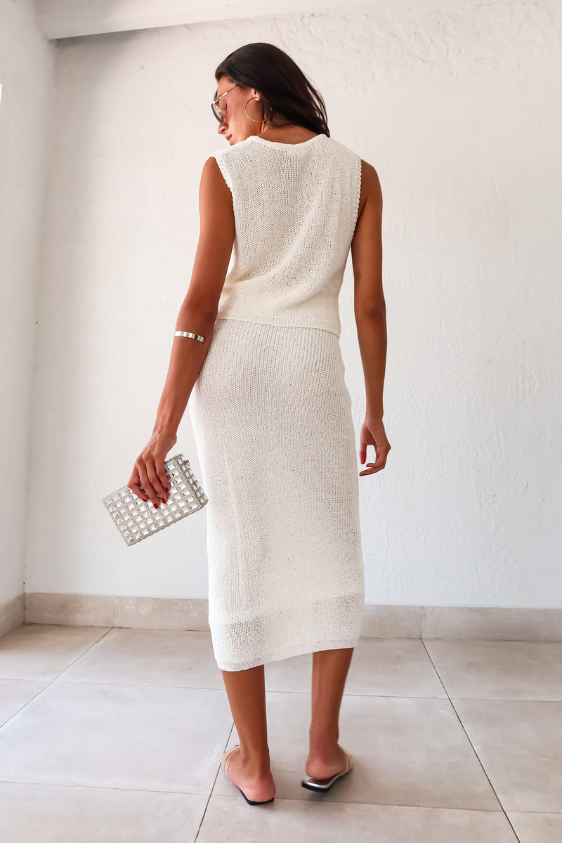  NIGHTS IN DUBAI KNIT SKIRT SET. This white knit set includes a sleeveless crop sweater top and a midi skirt with an elastic waist for a comfortable fit. The non-lined top and lined bottom are made of a stretchy polyester, rayon, and acrylic blend. 