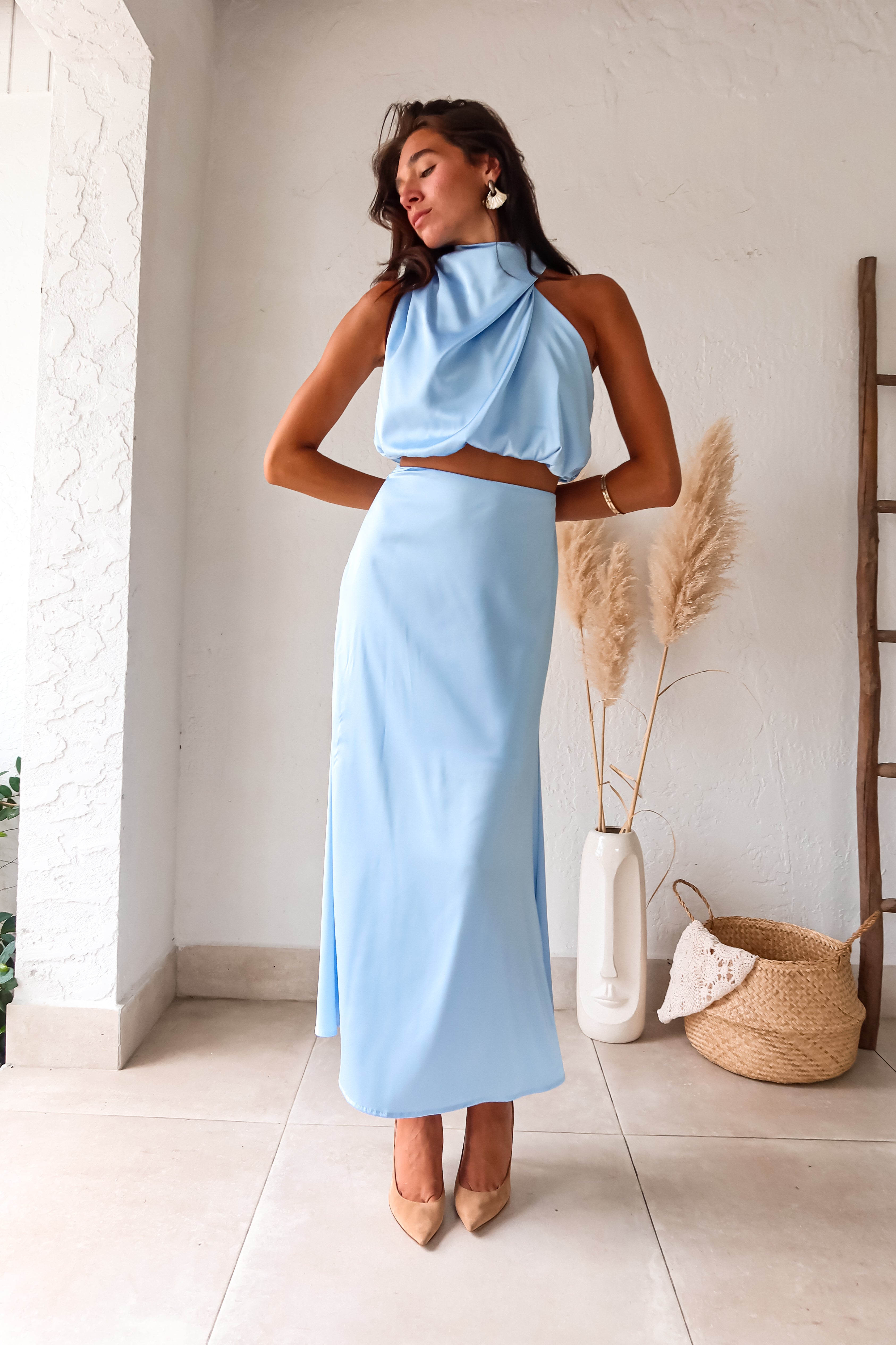 Look effortlessly chic in our Bellagio Satin Skirt Set! This sky blue stunner features a high neck asymmetrical top with functional buttons for added detail. The elastic scrunch fit ensures all day comfort, while the matching maxi skirt with side zipper closure adds a touch of elegance.