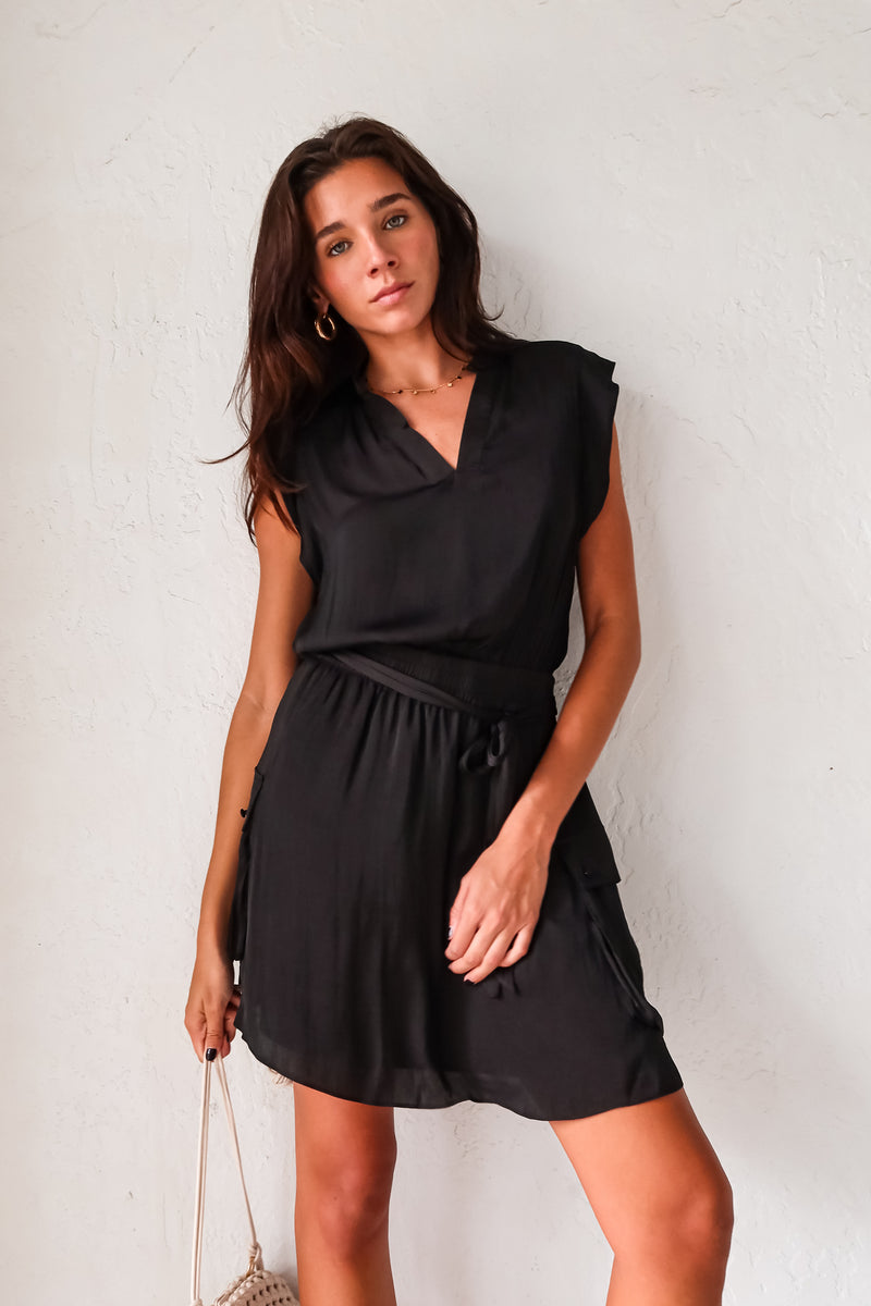 Get ready to turn heads in our Sunday Night Satin Mini Dress! This sleek black dress features a V-neck collar with shoulder padding for a structured look. The front tie sash adds a touch of femininity, while the side cargo pockets add a fun twist. With an elastic waist, you'll feel comfortable and confident all night long! (Elevate your style game with this quirky yet chic dress!)