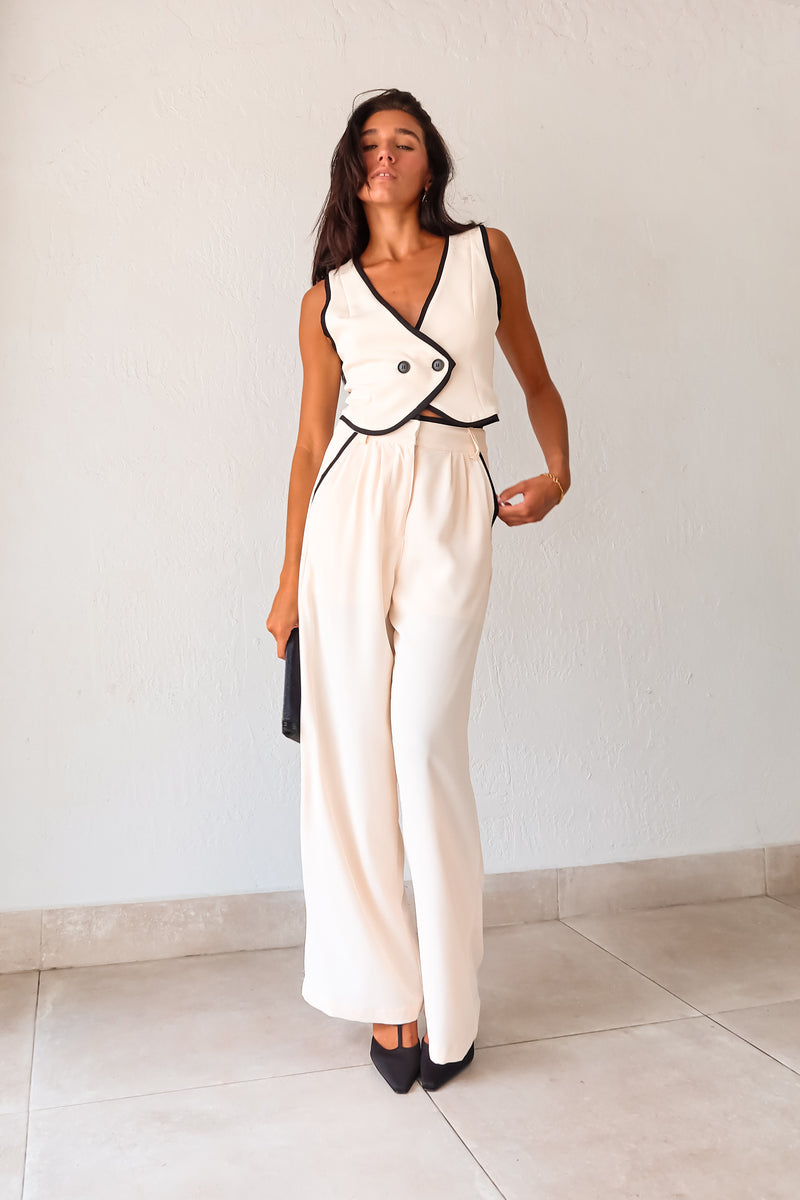 Unleash your inner fashionista with our BAL HARBOUR VEST PANT SET. This cream vest pant set features a unique black lining and an adjustable fit with a back buckle detail. The front button closure top and zipper clip closure pants provide practicality, while the front pockets add a touch of functionality. Sophisticated yet playful, this set will elevate your wardrobe. 