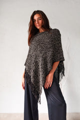 Embrace your wild side with our FULL MOON LUREX PONCHO. The black lurex sweater poncho features silver fabric detailing, a fringed bottom, and stretchy fabric for a comfortable fit that flatters any size. Perfect for a night out or cozying up by the fire. One size fits XS-L.