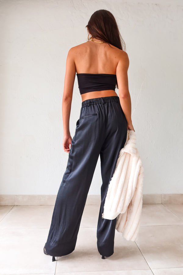 Slip into sleek style with the MONTMARTRE TROUSER in black. These satin trousers feature a zipper clip closure and elastic waist backing for a comfortable fit. With front pockets and belt loops, this pant is both functional and fashionable. Elevate your look with this versatile and chic piece!