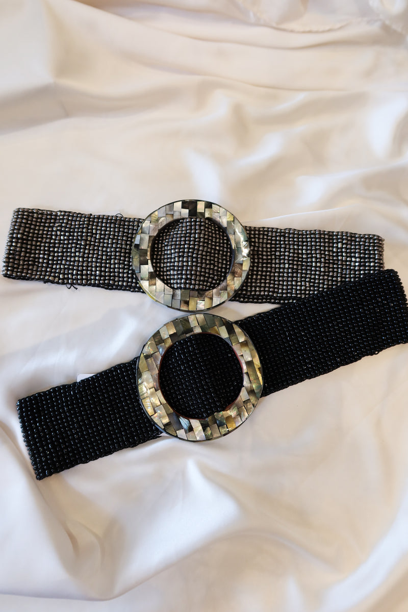 OZ Beaded Belt! Handcrafted in Bali, this stretchy and versatile belt features a unique abalone circle buckle and beautiful black or silver beading. One size fits all, making it the perfect accessory for any outfit.