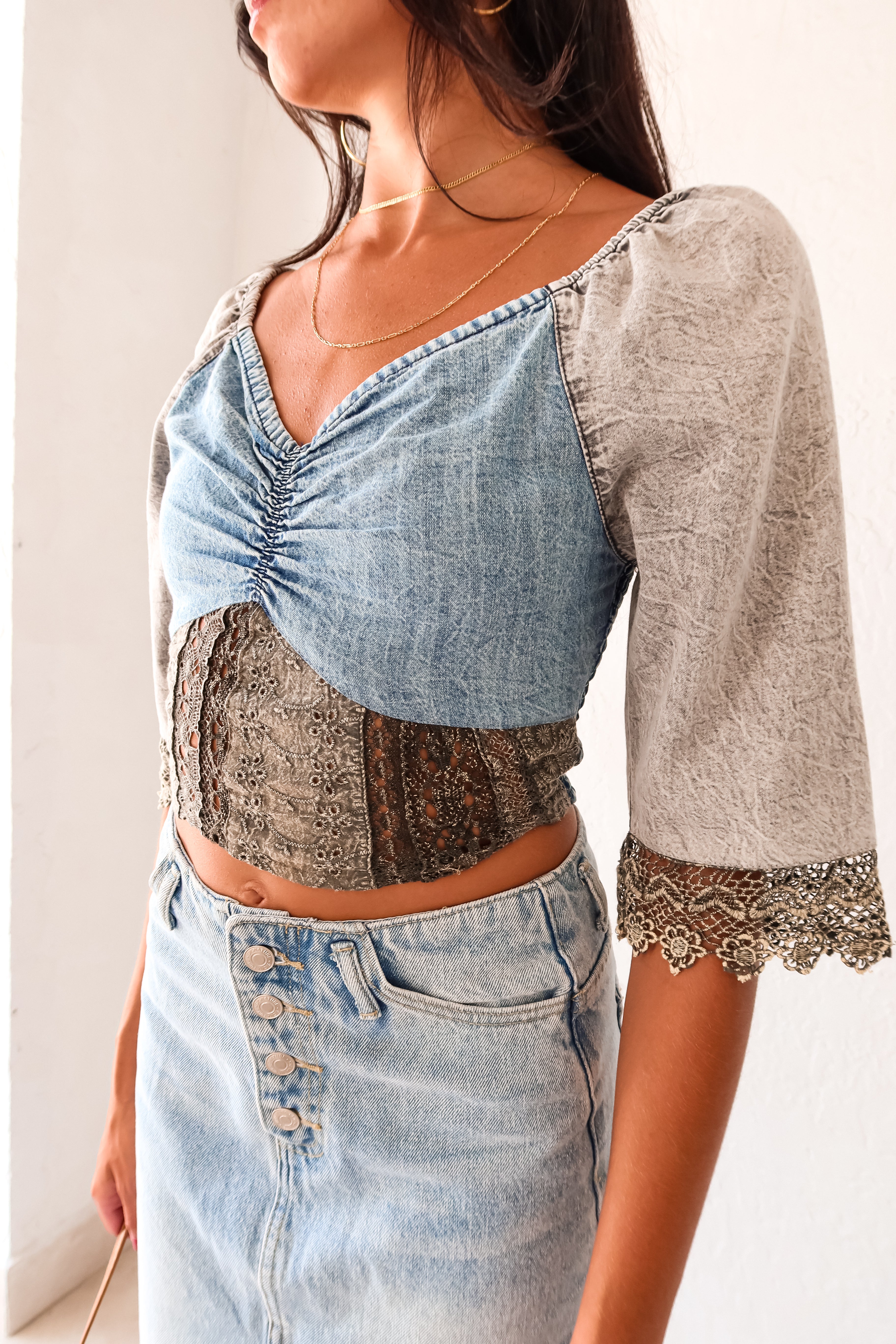 Queen Denim Crop Top! This mix denim crop top features a smock back for a comfortable fit and 3/4 sleeves with a unique crochet design. With elastic at the shoulders, you can easily switch up your look for an on or off shoulder style. The slight stretch and true to size fit make it a perfect staple for any occasion. And best of all, it pairs perfectly with our Melrose Denim Midi Skirt.