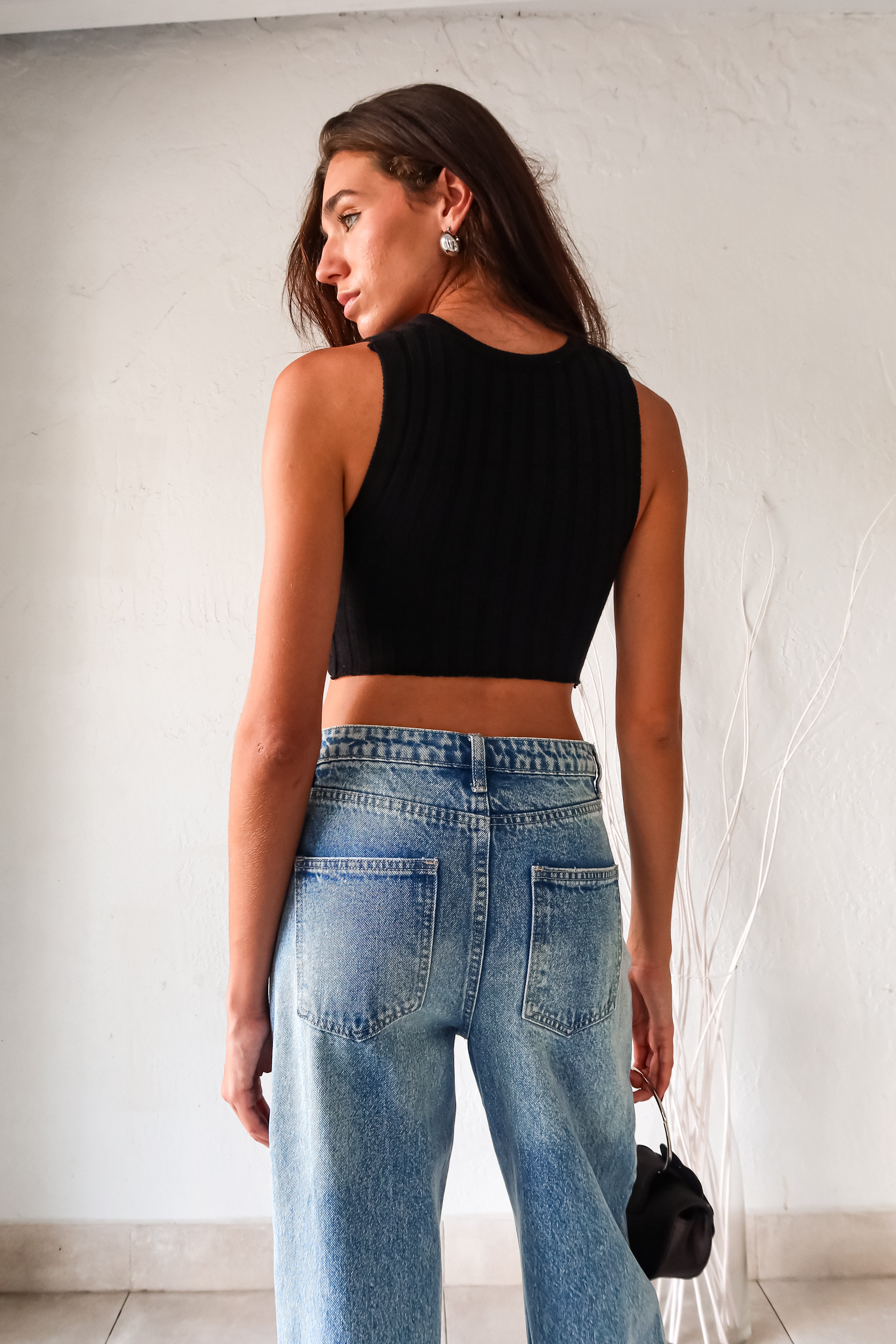 Add some edge to your wardrobe with our black ribbed crop top! Featuring a unique neck chain detail and front overlap design, this top is sure to turn heads. The stretchy fabric ensures a comfortable fit for all-day wear.