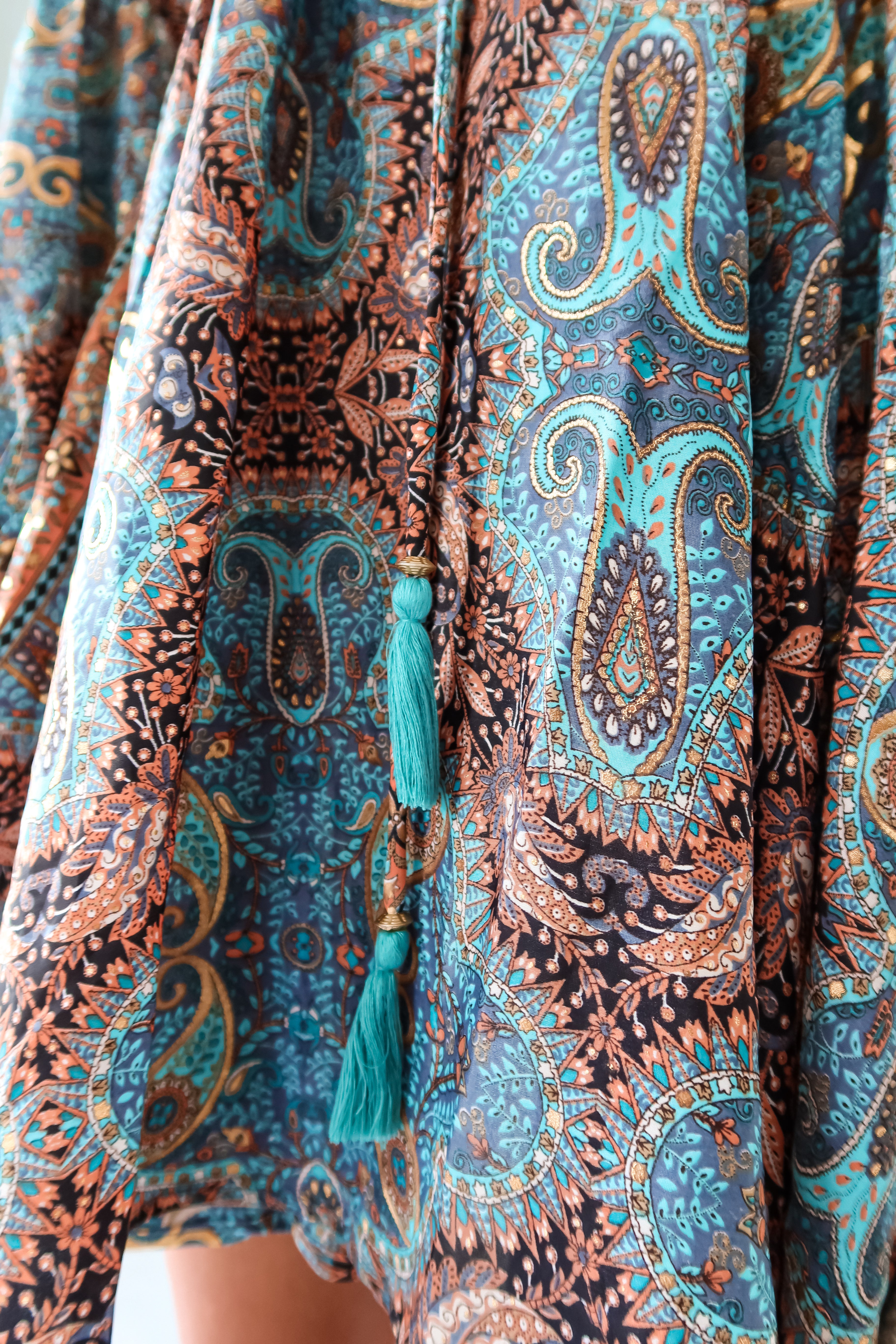 Add some playful flair to your wardrobe with our Barcelona Long Sleeve Mini Dress! Featuring a vibrant turquoise, gold, black, and orange floral paisley design, this dress will surely turn heads. The long sleeves with bubble wrists and front button closure with waist tie string add unique touches to this one-of-a-kind piece.