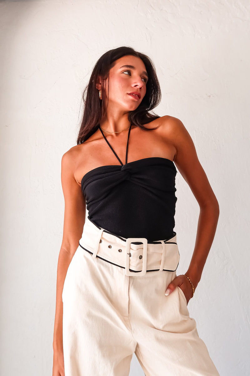 Effortlessly chic and comfortable, the ECLIPSE KNIT TOP in black is a must-have for your wardrobe. Made with ribbed stretchy fabric, it features a front knot design and a unique tie around the neck. Perfect for pairing with the Napoli Belted Linen Pant and the Silvana Woven Tote. Don't forget to size down for the perfect fit!