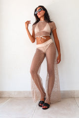 versatile and stylish cover up for your next beach day? Look no further than the MALIBU PANT SET - GOLD! With its shimmering gold fabric and 1/4 sleeve crop top with a torso tie string, this set is both glamorous and practical. The stretchy satin waistband ensures a comfortable fit, and it runs true to size. Add the Azusa/Cerritos Bikini Habano Nude for the perfect beach outfit. Made by ALILA SWIM.