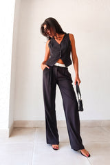 The Melrose Place Vest Pant Set is the perfect combination of style and quirkiness. The black vest and pants feature unique details such as an open back with adjustable buckle silver detail, front button closure, and pleated pants with a white detail waist. Stay comfortable and trendy 