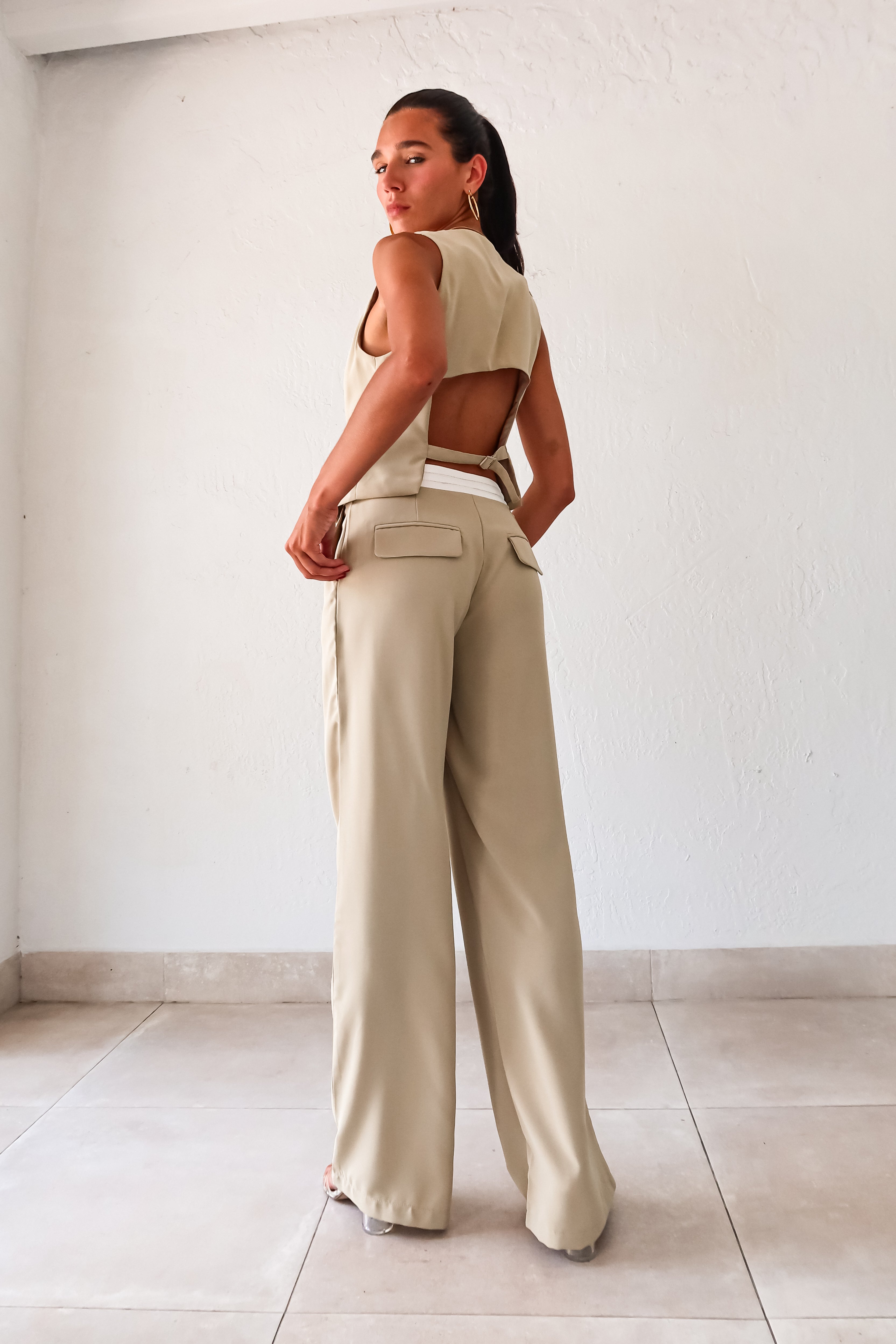 This sage green vest pant set adds a touch of charm to your wardrobe. Features a top with adjustable buckle silver detail and front button closure, while the pants offer a pleated design with white waist detail and front pockets. 