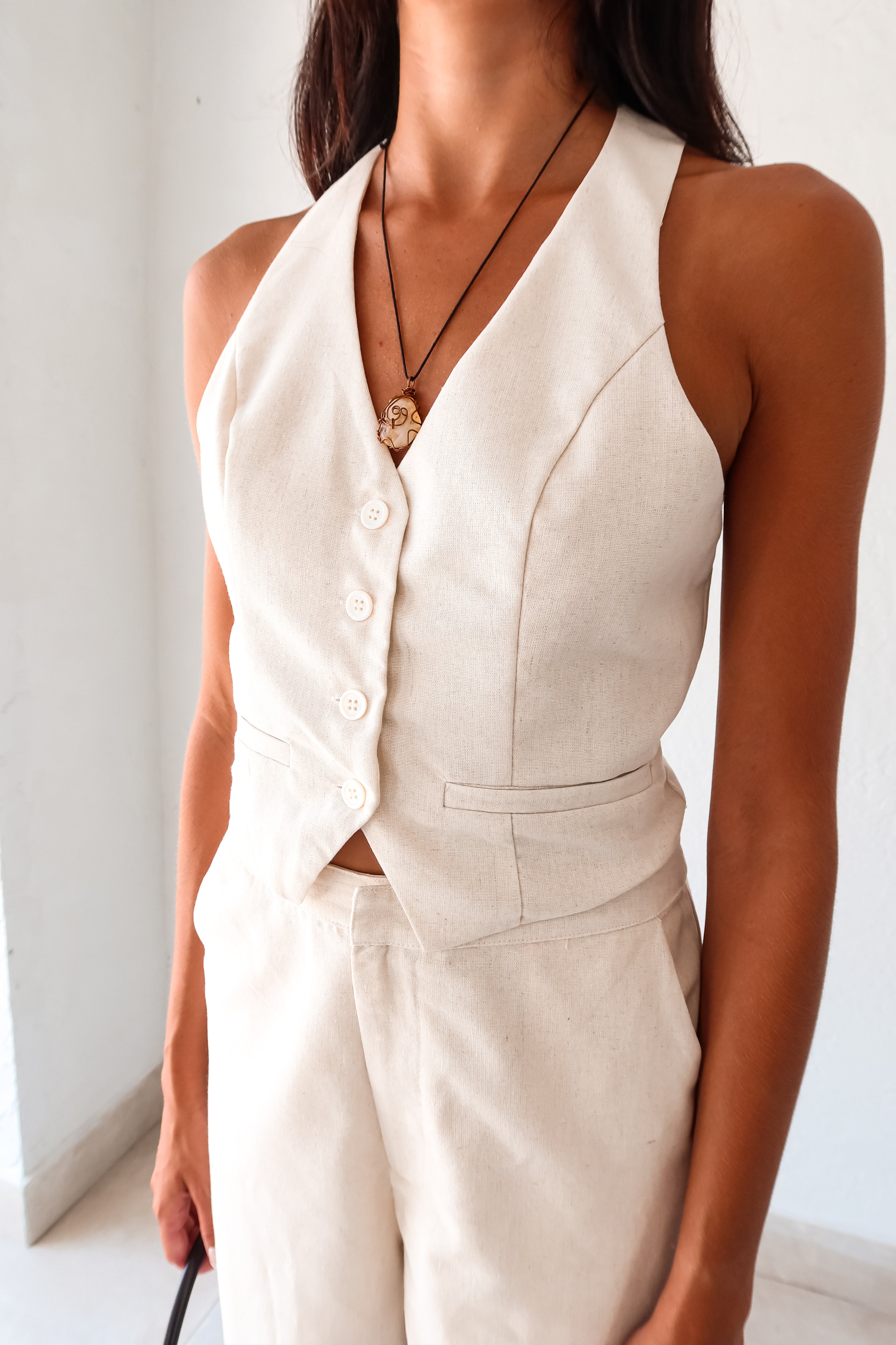 On the Boardwalk Linen Jumpsuit! This beige linen jumpsuit features a vest top with front button closure pocket detail and an open torso for a breezy look. With a bottom zipper clip closure and lining, this non-stretch jumpsuit is perfect for a day out. Runs true to size, Sofia wears size small. Made with a blend of Viscose, Linen, and Polyester