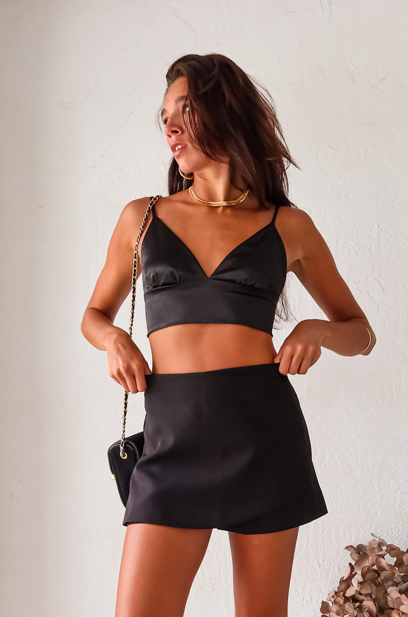 Elevate any outfit with this playful black satin bralette. The triangle top and adjustable shoulder straps provide a comfortable fit, perfect for a girls night out. The elastic backing adds a touch of quirkiness to this must-have piece.