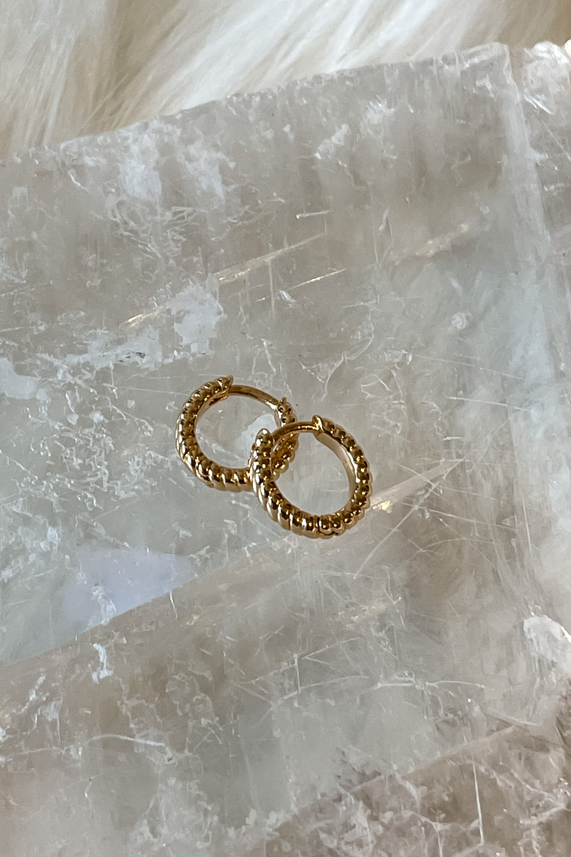 Add a twist to your style with these gold huggies. The stainless steel material ensures they won't turn color or tarnish, while the clasp closure offers a secure fit. Measuring 1 inch wide with a playful twist design, these huggies are a stylish addition to any outfit.