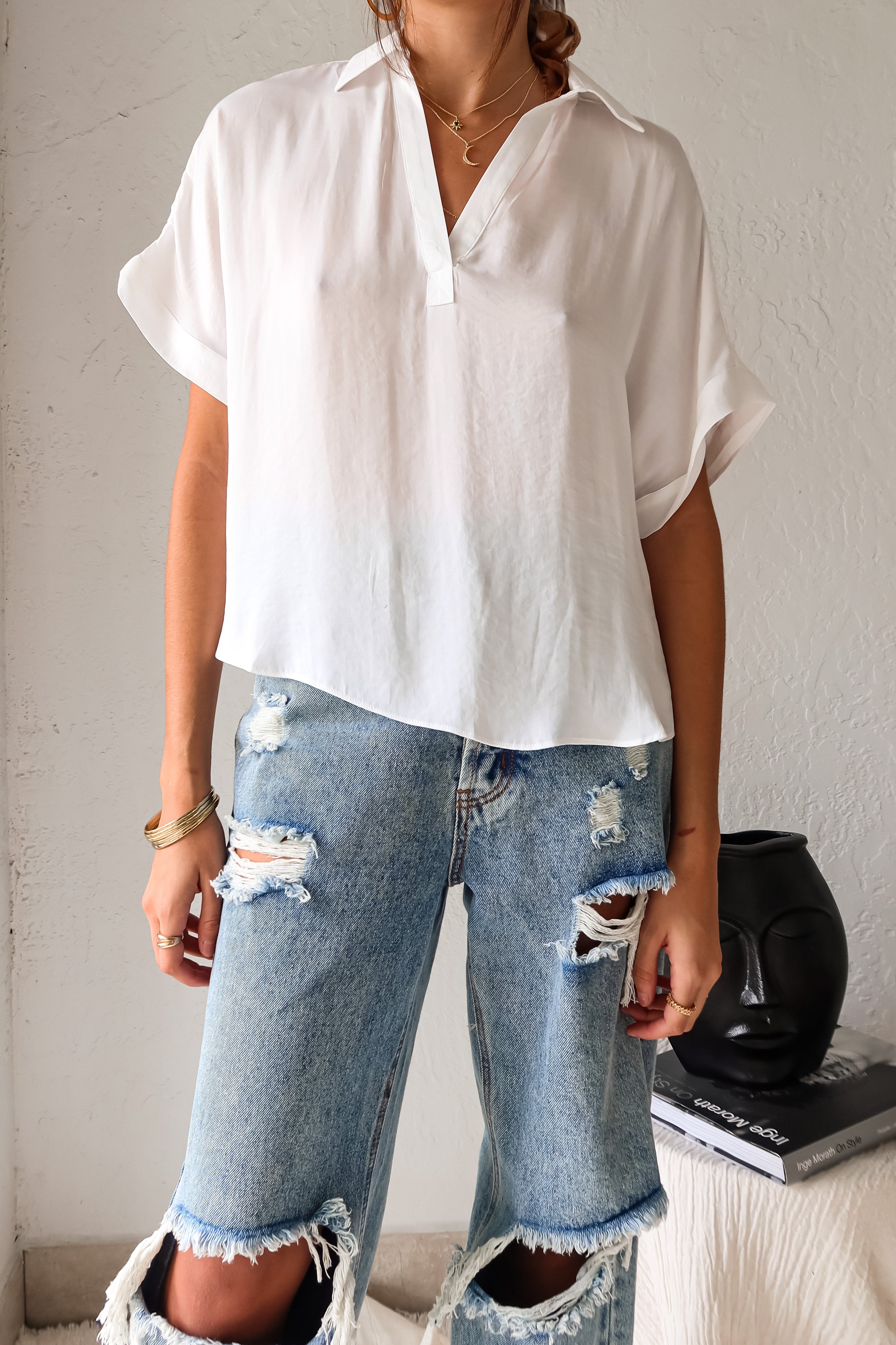  DOWNTOWN BLOUSE in classic white is a best seller for a reason. With a v-neck collared design and lightweight satin feel, this top is effortlessly chic. The cuffed sleeve adds a touch of sophistication. 